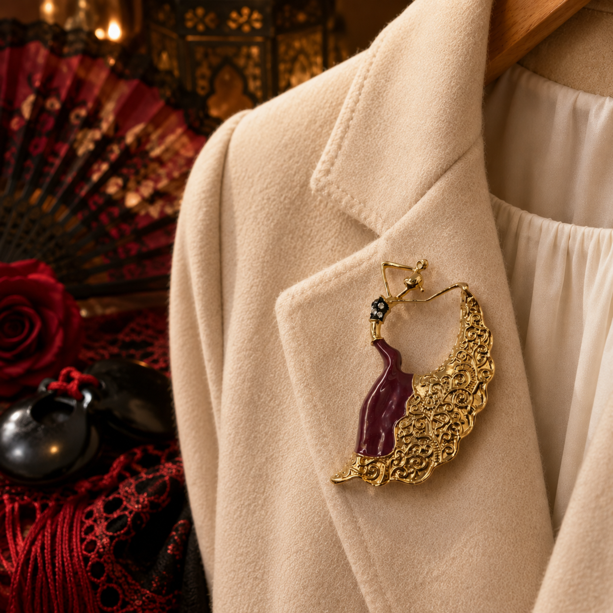 Gold-tone dancing woman brooch with burgundy enamel dress, ornate flowing skirt and sparkling rhinestone detail. Shown on lapel of cream jacket with red Spanish theme background.