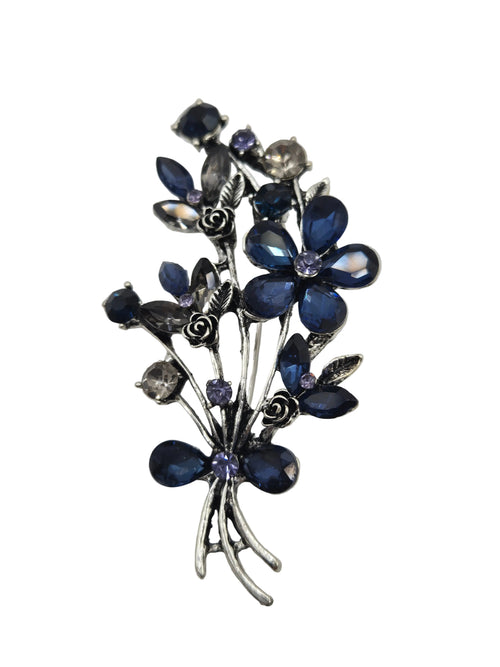 Silver brooch with blue gemstones on a gray background