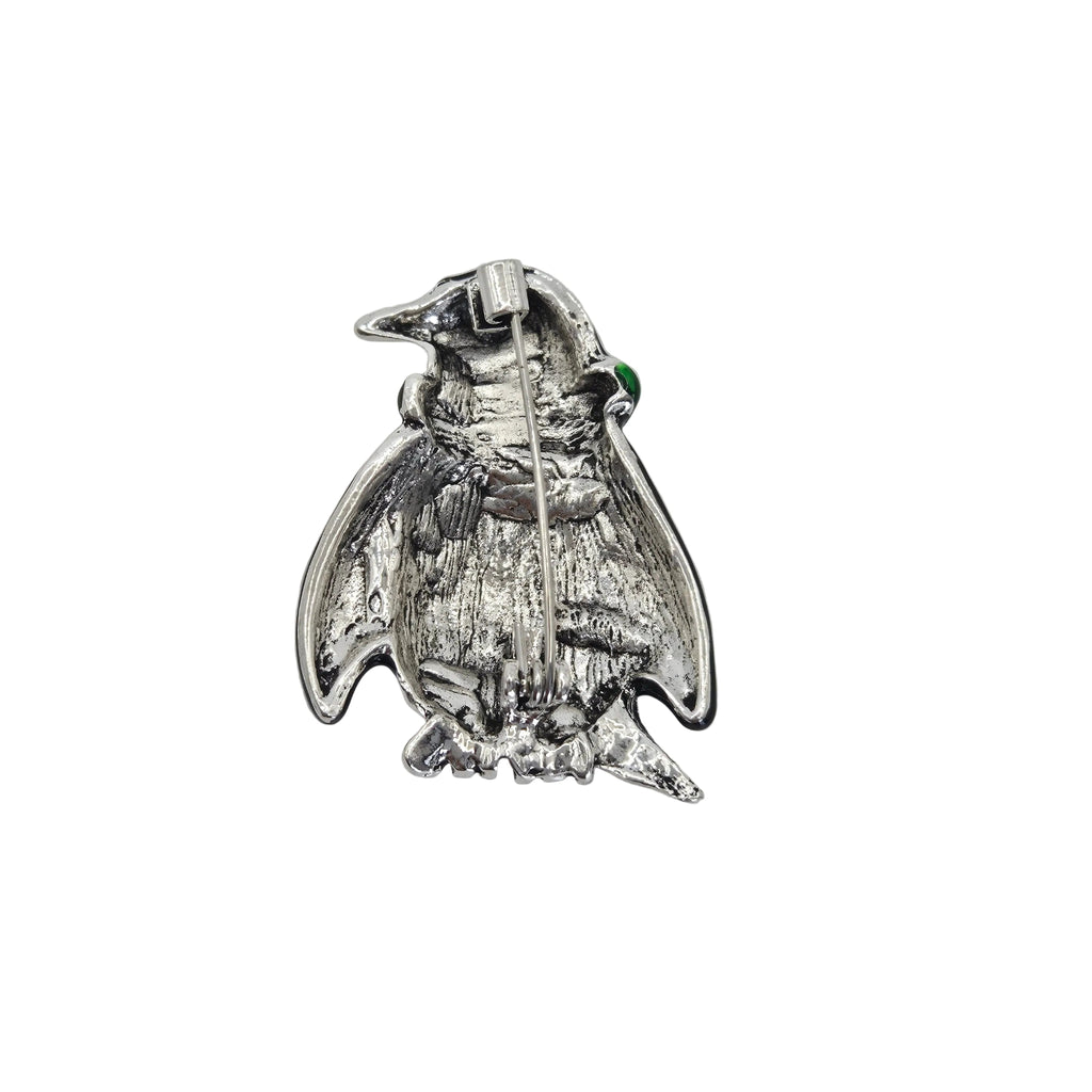 A silver penguin brooch with a small green gemstone accent, shown on a plain white background.
