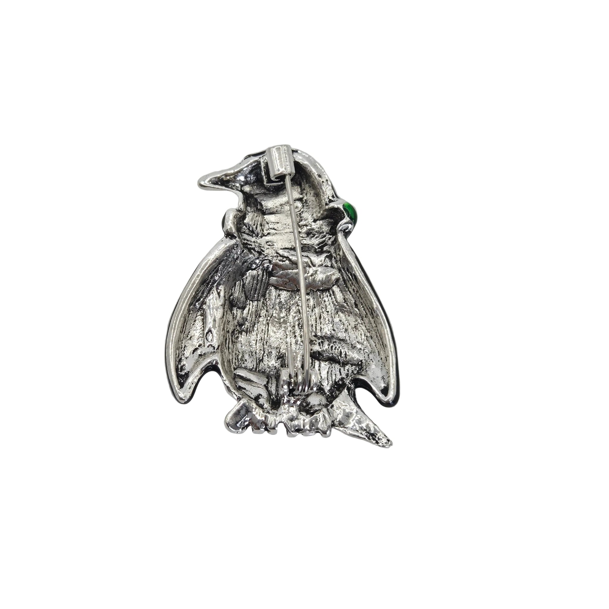 A silver penguin brooch with a small green gemstone accent, shown on a plain white background.