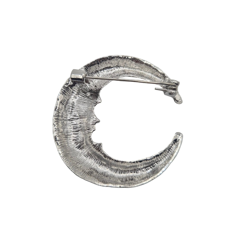 A textured silver crescent moon brooch showing the reverse side with a textured, hammered finish, shown on a plain light white background.