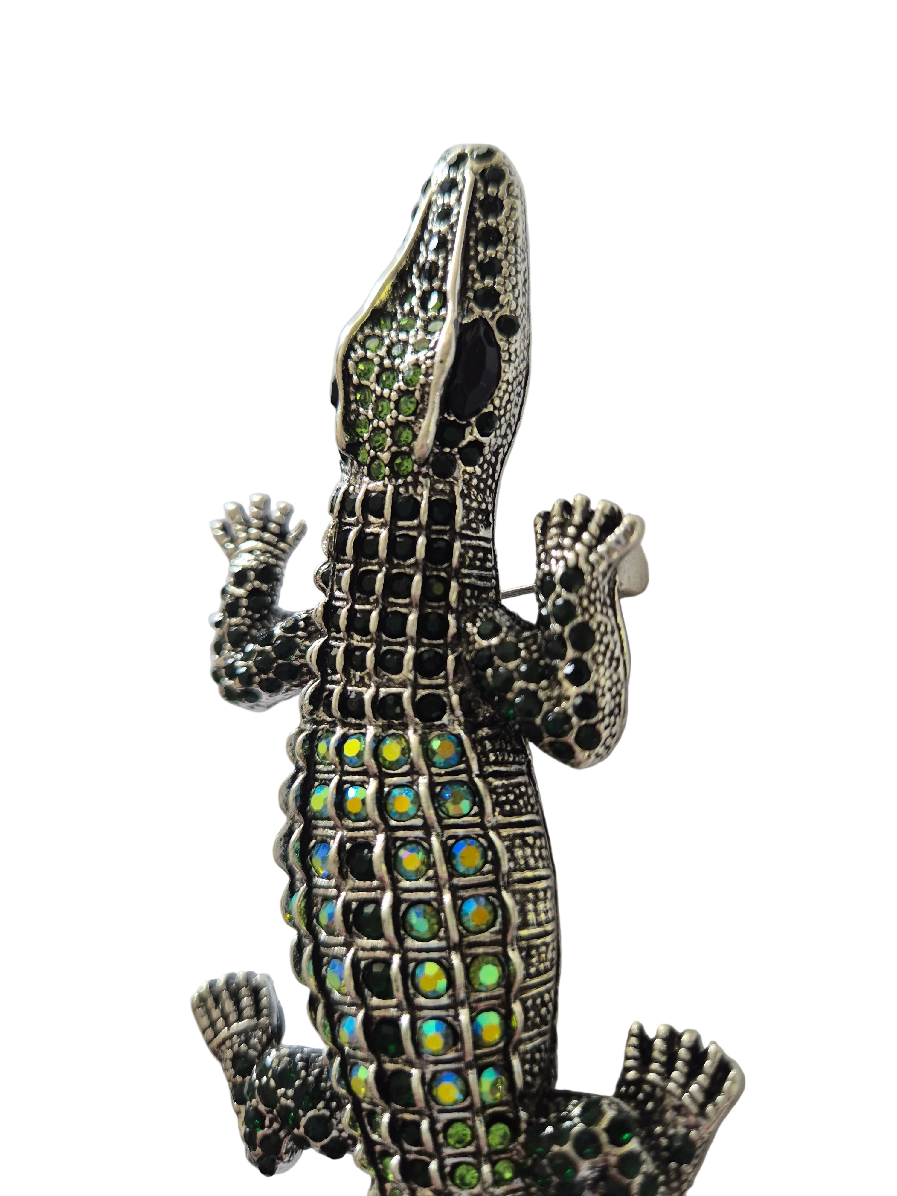 Decorative crocodile brooch with gemstone accents on a white background