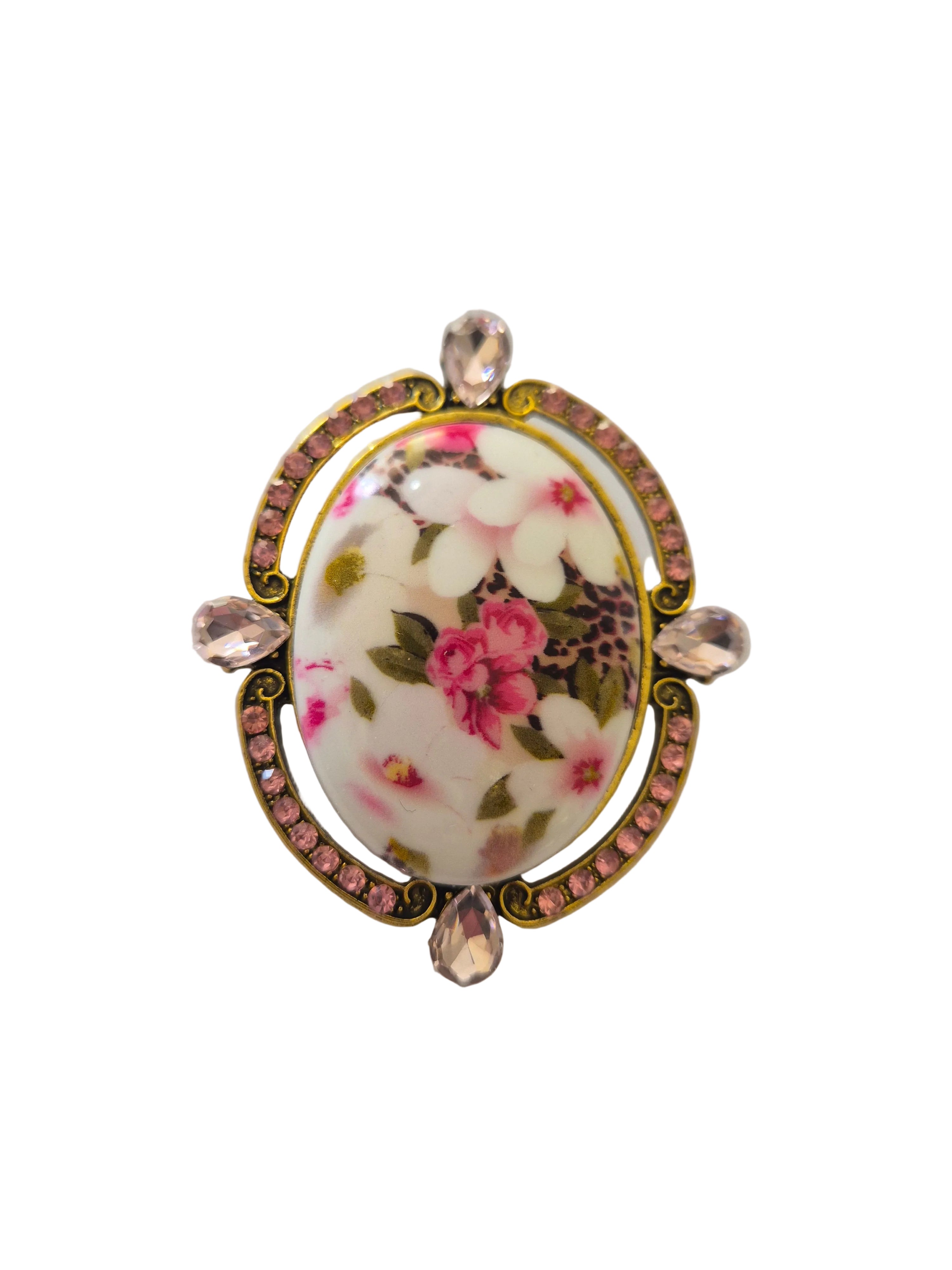 Decorative brooch with floral design and pink gemstones on a white background