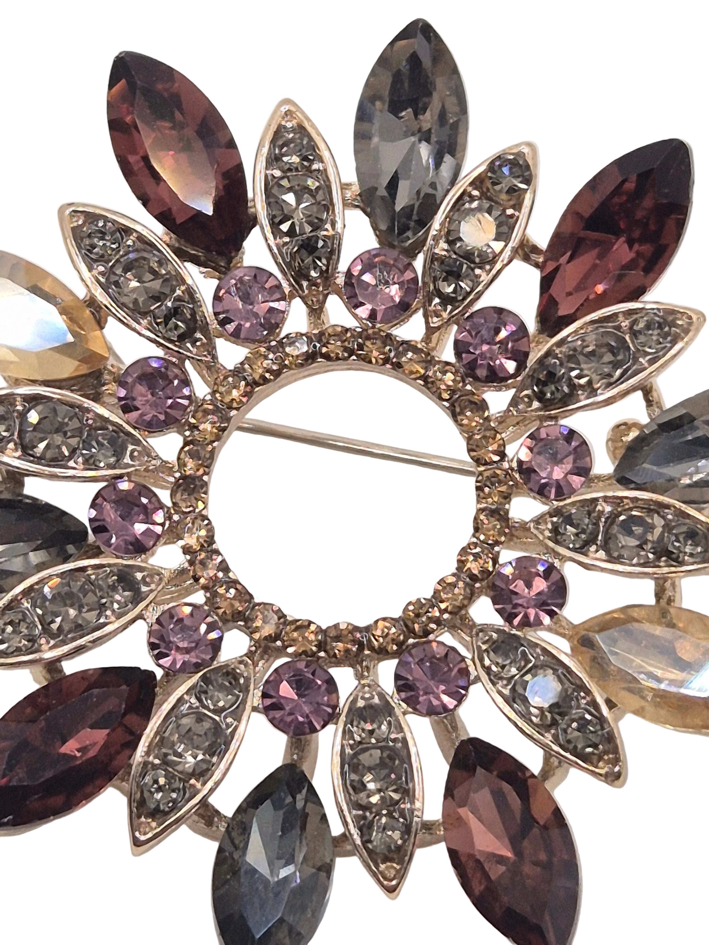 Decorative wreath brooch with multicolored gemstones on a white background