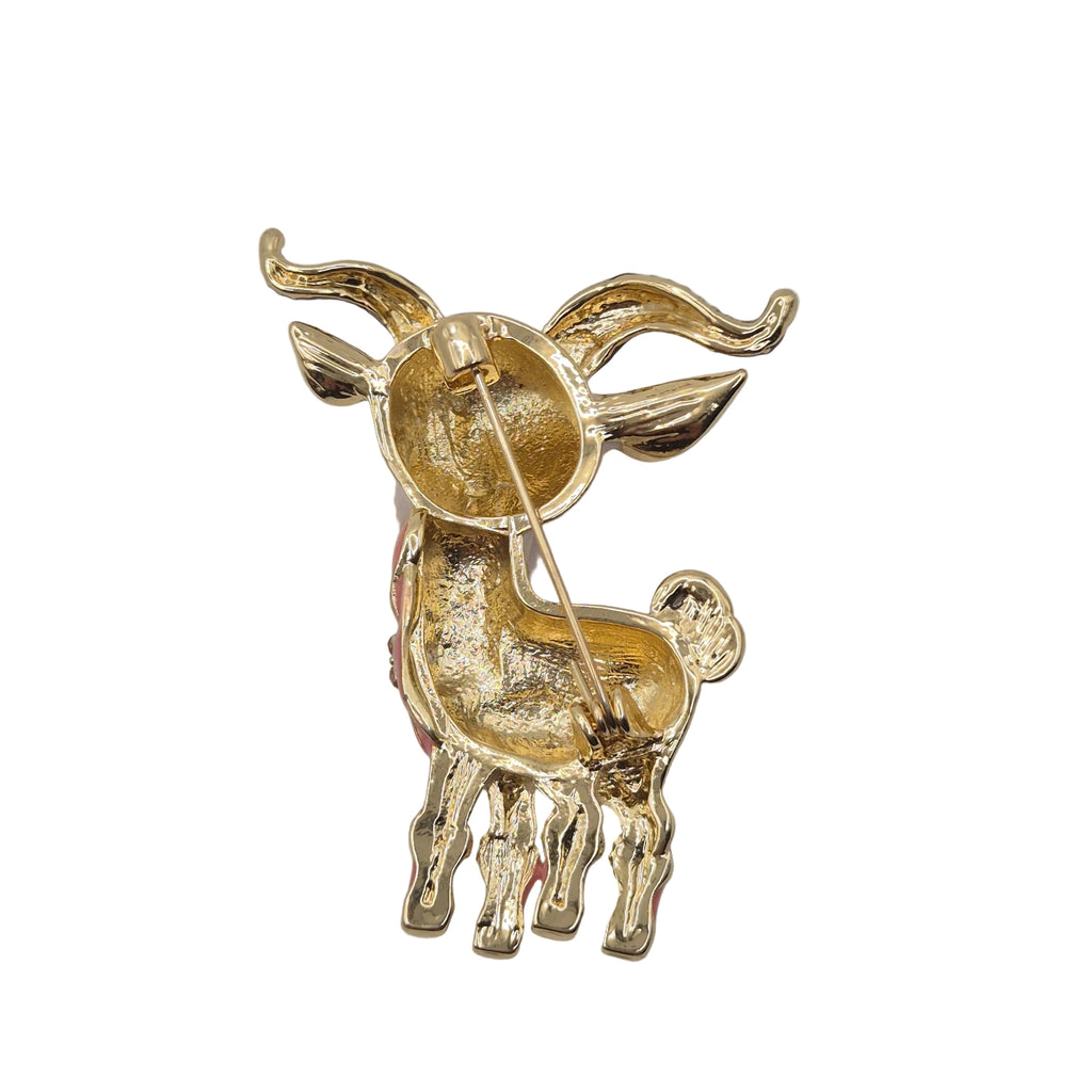 A gold-tone goat or ram-shaped brooch with curved horns and a pin fastener visible on the underside, photographed against a plain white background.