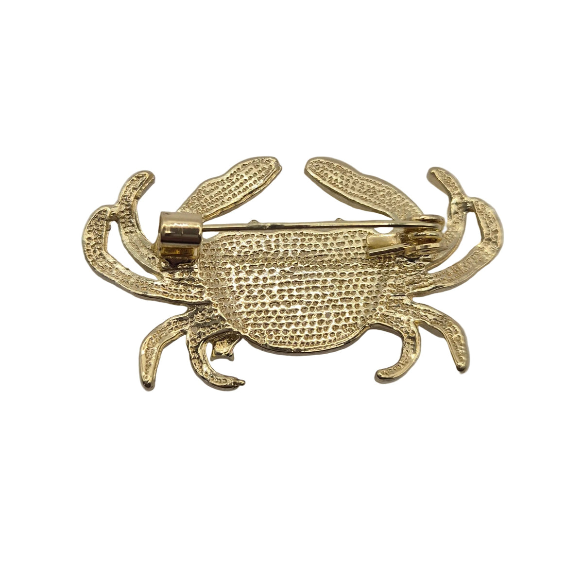 A gold crab-shaped pin brooch with a textured, mesh-like surface and a visible safety pin clasp, photographed on a plain white background.