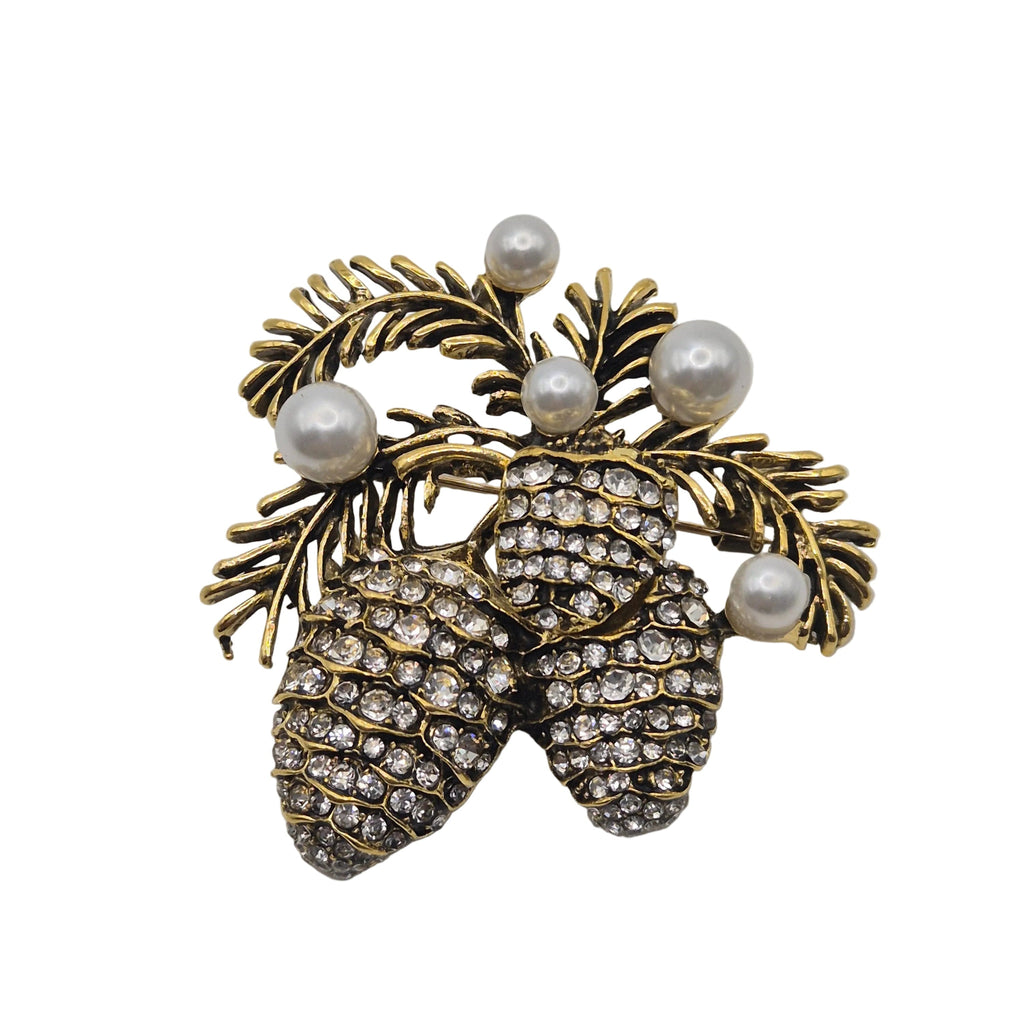 A vintage-style pinecones and evergreen branch brooch in gold-tone metal, embellished with clear rhinestones on the pinecones and white faux pearls.