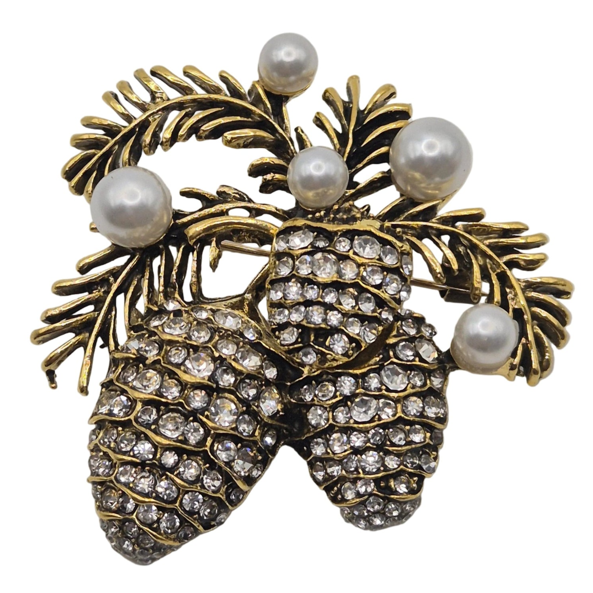 A vintage-style pinecone brooch featuring two gold-tone pinecones set with clear rhinestones and accented by four white faux pearls on a gold-tone pine branch background, shown on a plain white background.