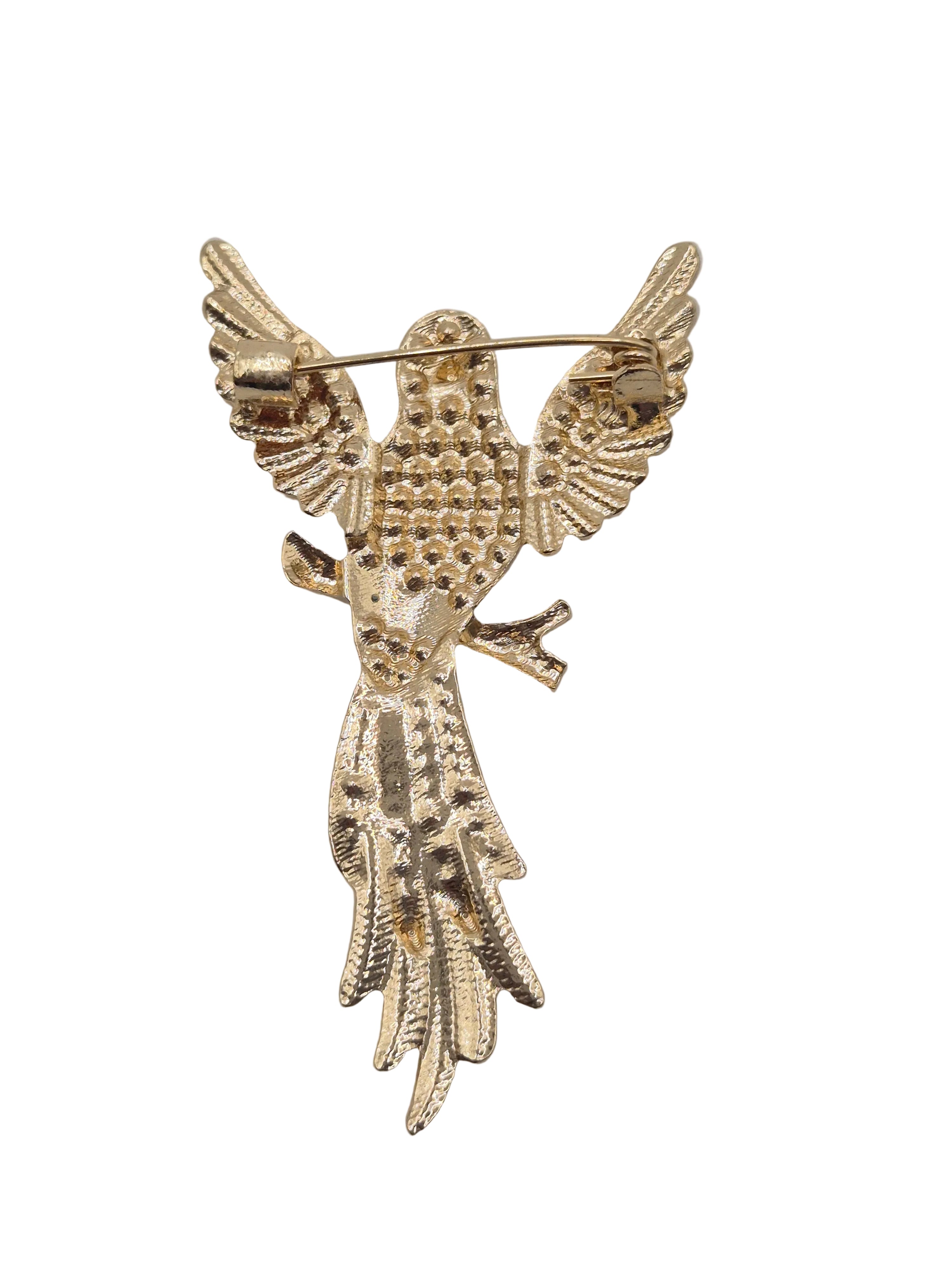 A gold-toned metal bird brooch with outstretched wings and a textured beaded body, shown on a plain white background.