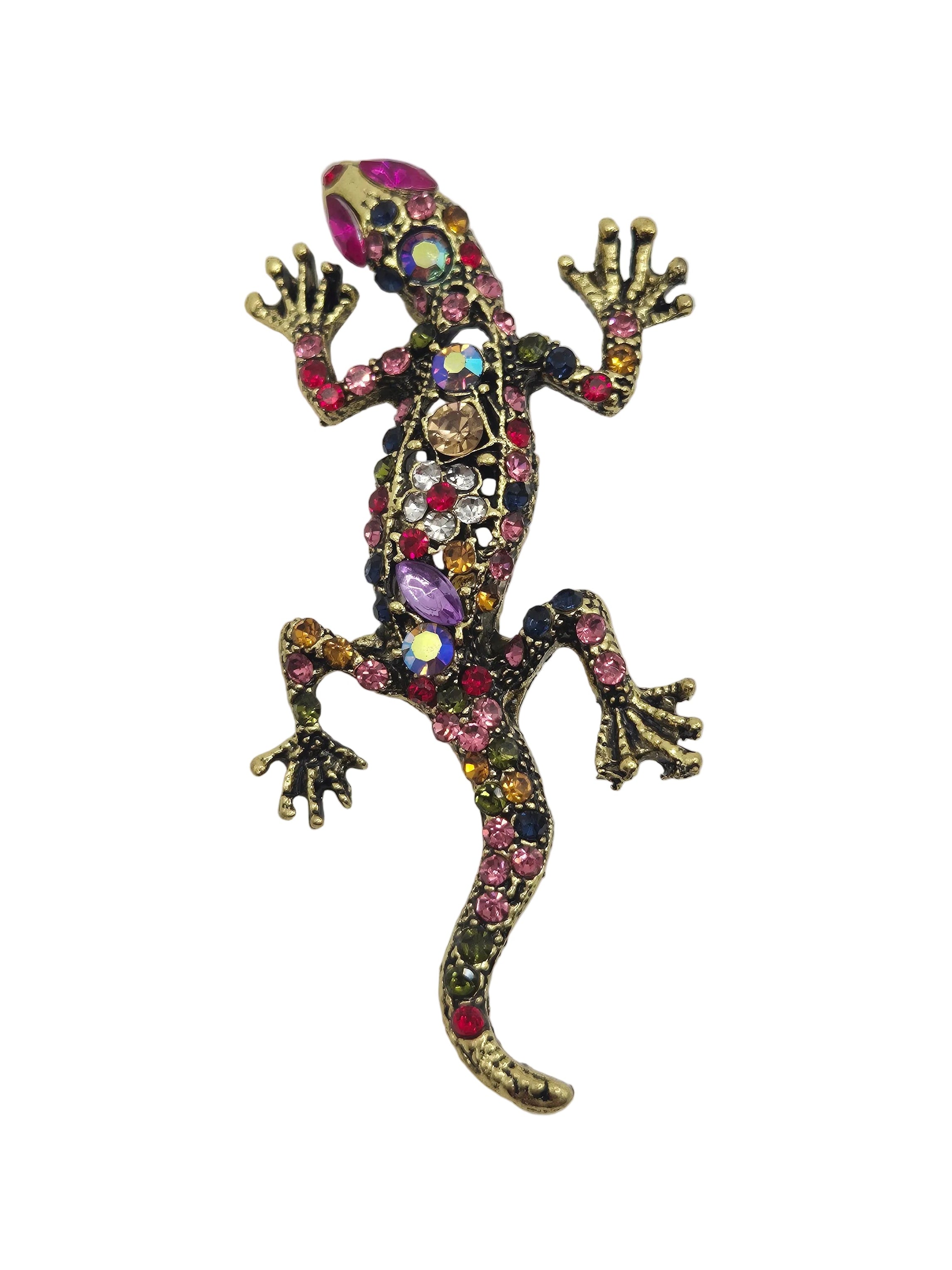 A gecko-shaped brooch embellished with multicolored rhinestones and set in a gold-tone metal, shown against a plain white background.