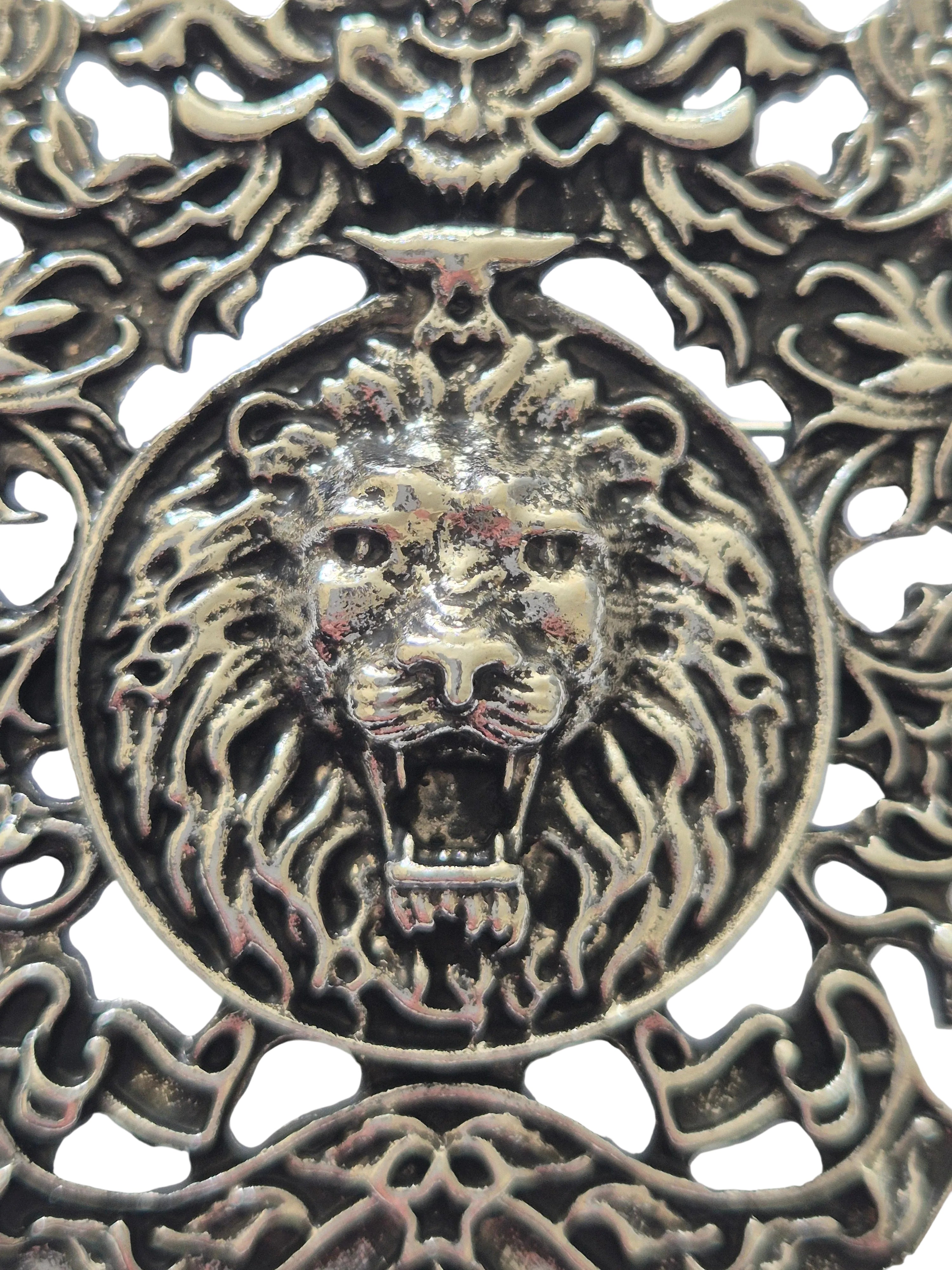 silver lion's head design brooch on a white background
