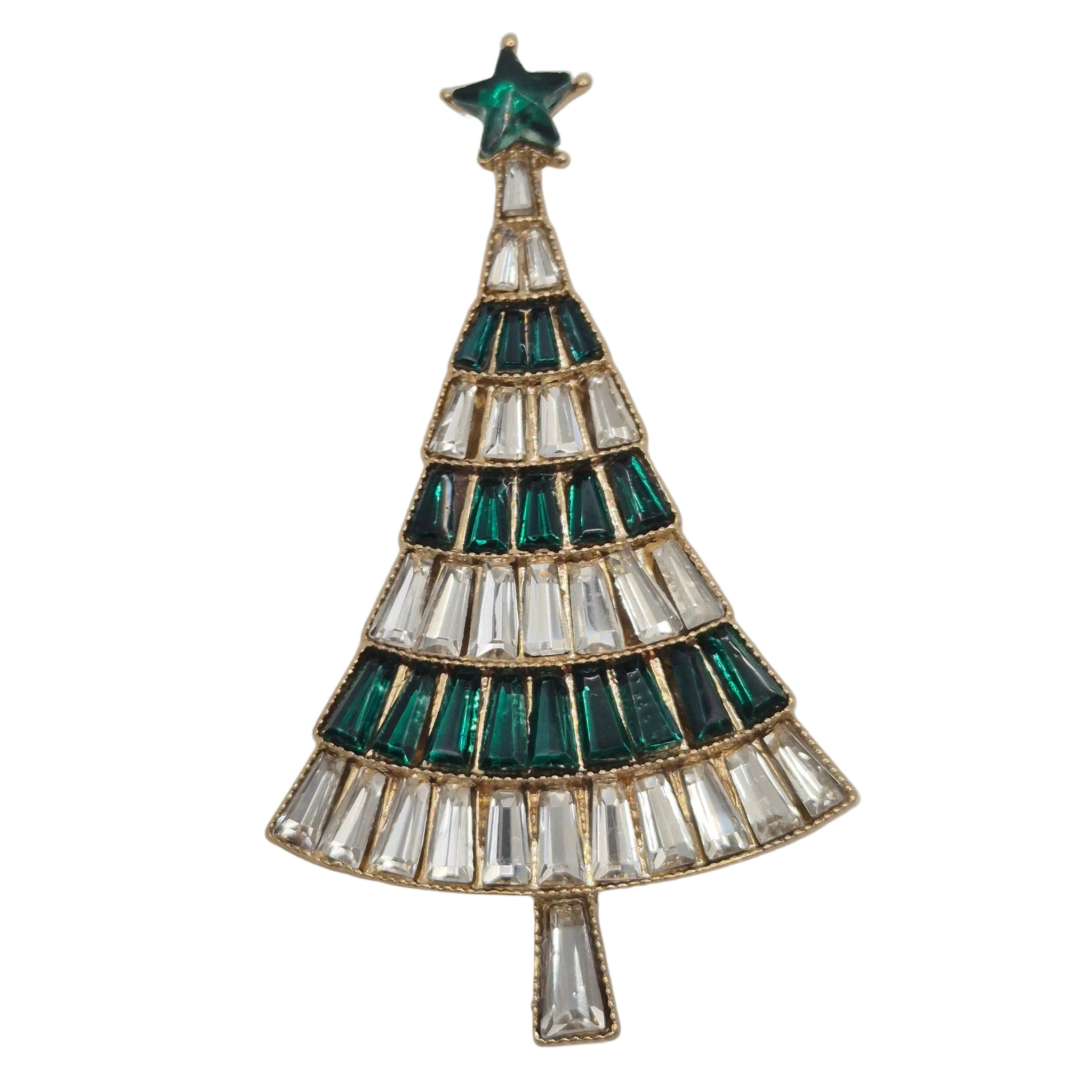 A gold-tone Christmas tree brooch featuring green and clear faceted crystals, set against a plain white background.
