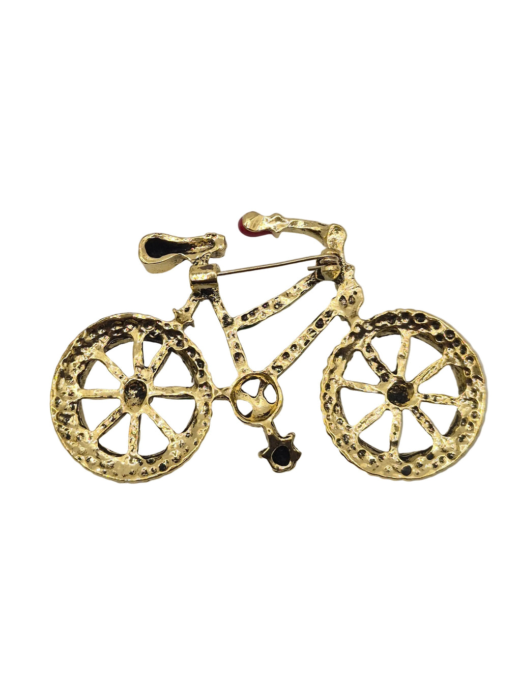 A gold bicycle-shaped brooch with textured details and small dark gemstone accents on the wheels, shown against a plain white background.
