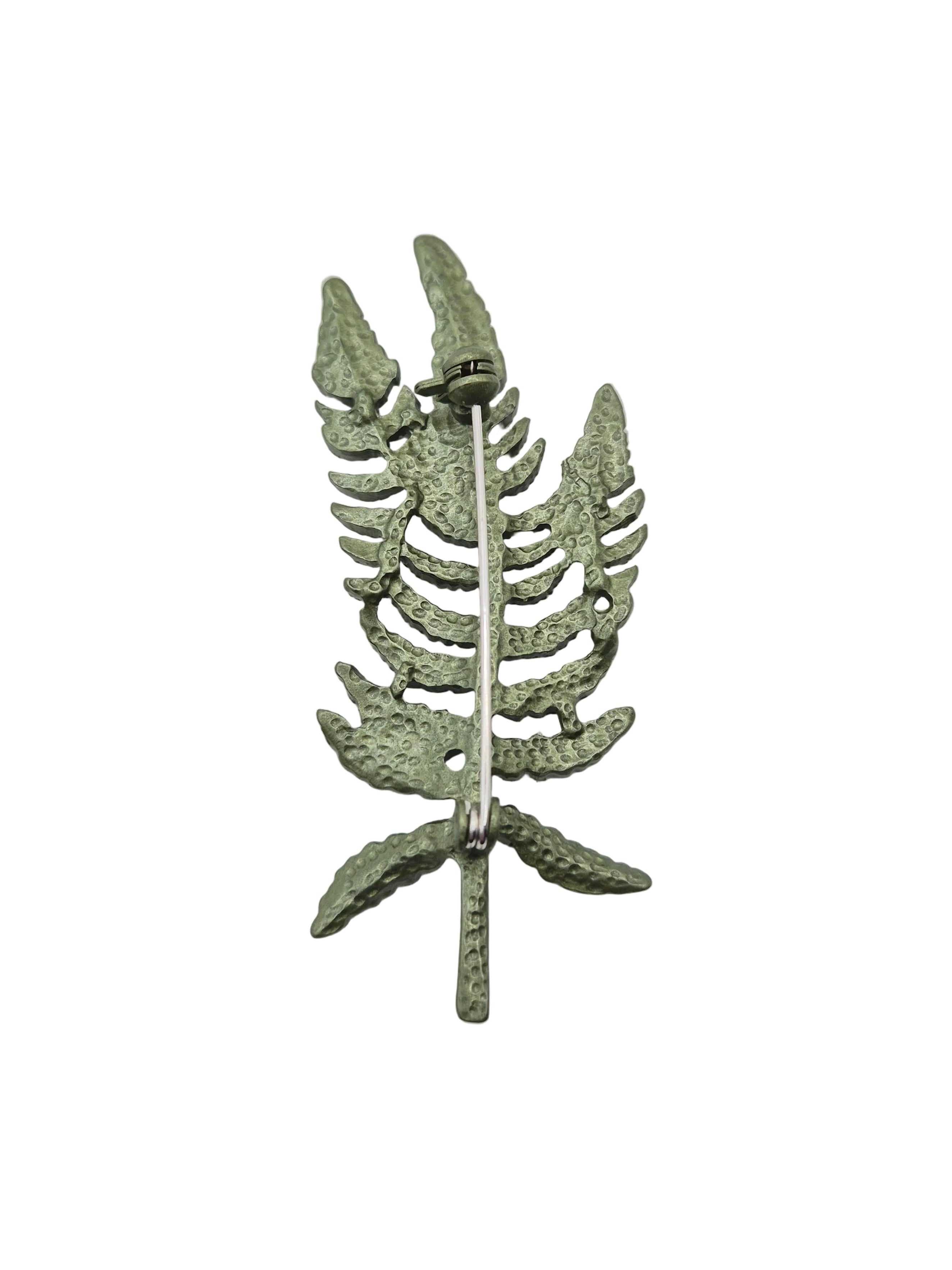 Reverse side of green fern leaves brooch on a plain white background. 