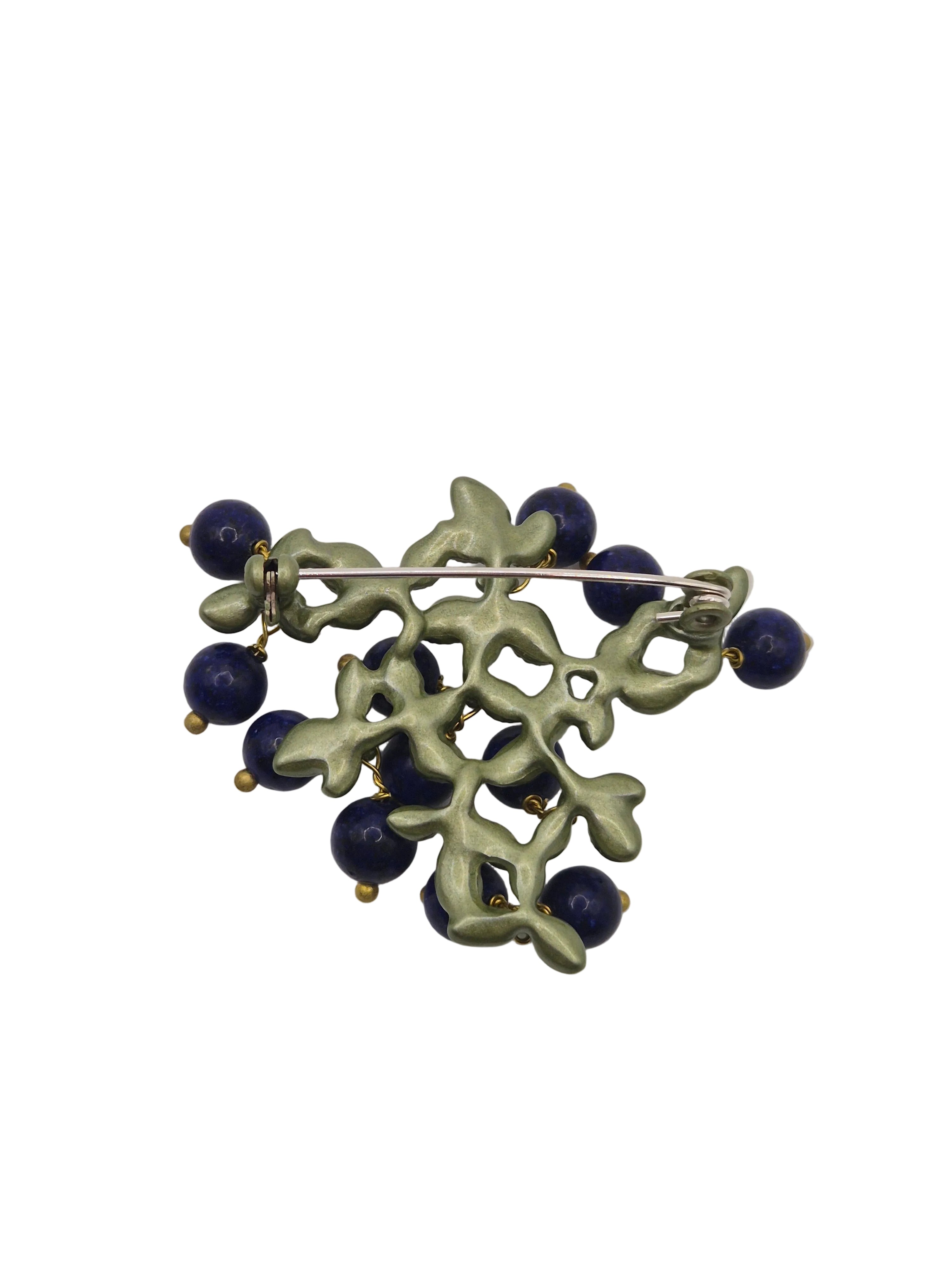 Brooch with green leaves and blue berries on a white background
