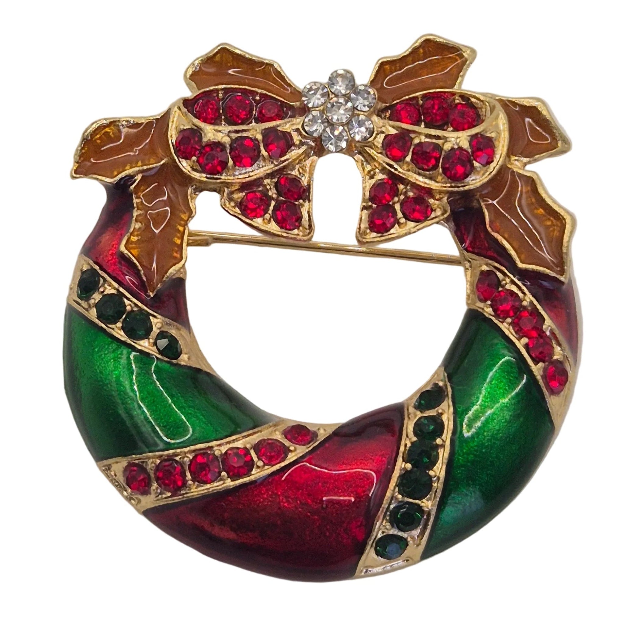 A gold-plated Christmas wreath brooch featuring vibrant green and red enamel, accented with red rhinestones, brown holly leaves, and a central cluster of clear rhinestones.