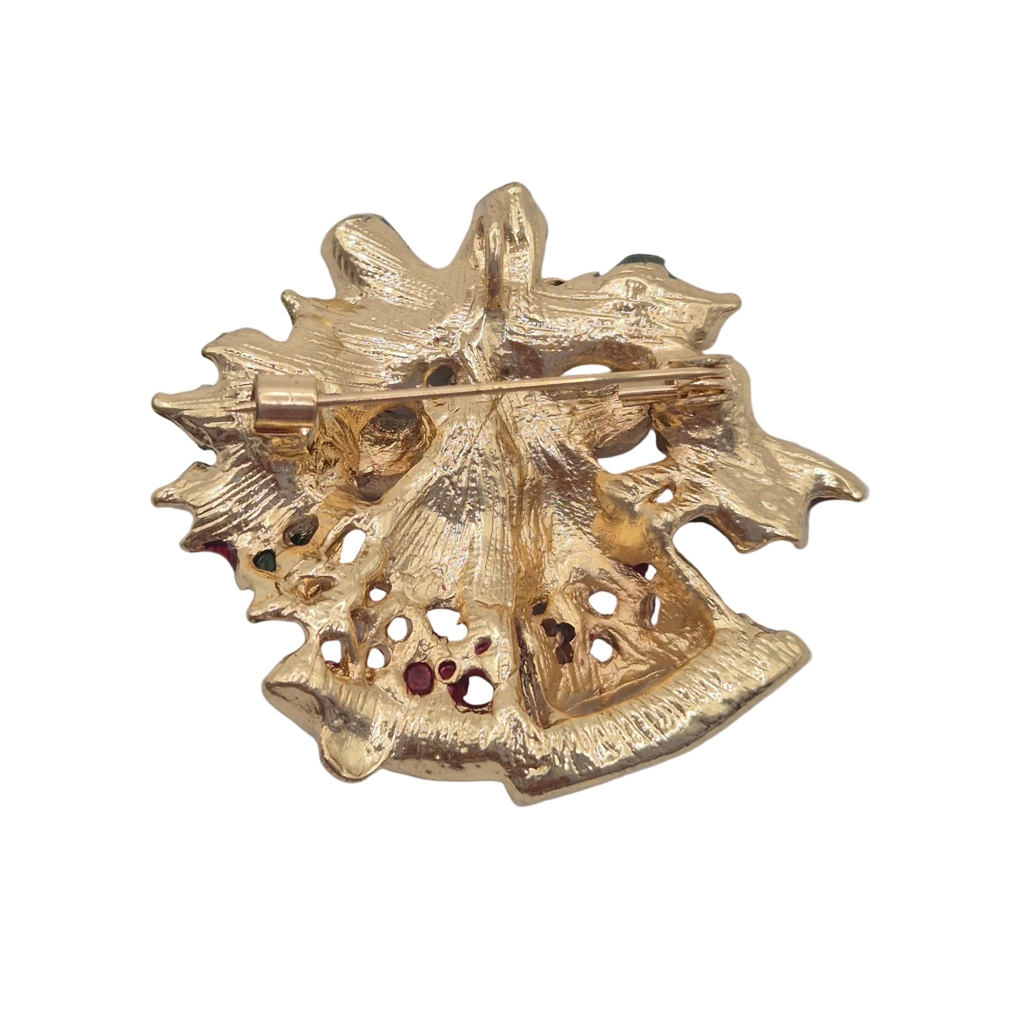A textured gold-tone brooch shaped like like Christmas bells with openwork details and a pin fastener visible on the reverse side, shown against a plain white background.