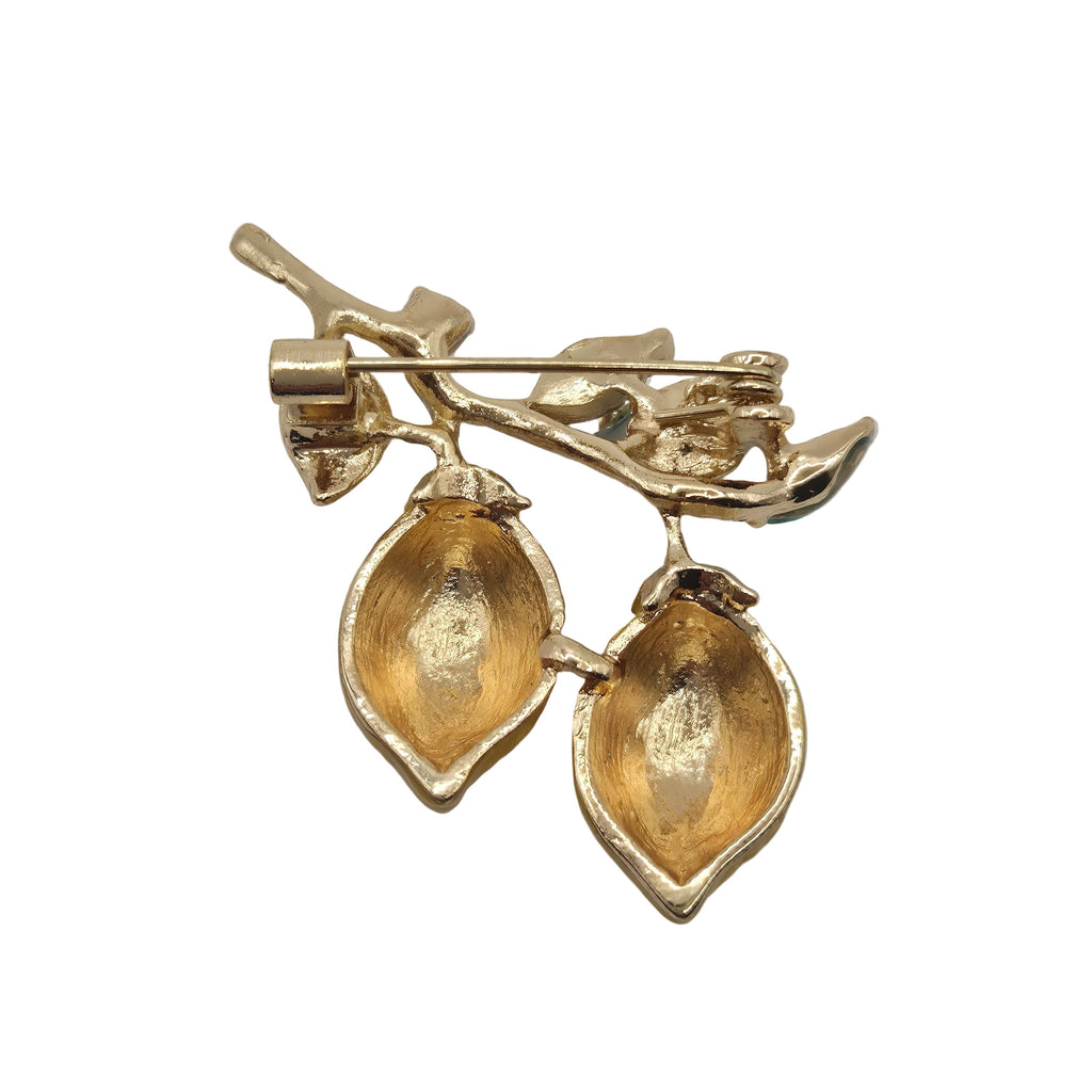 Gold lemon brooch with leaf design on a gray background