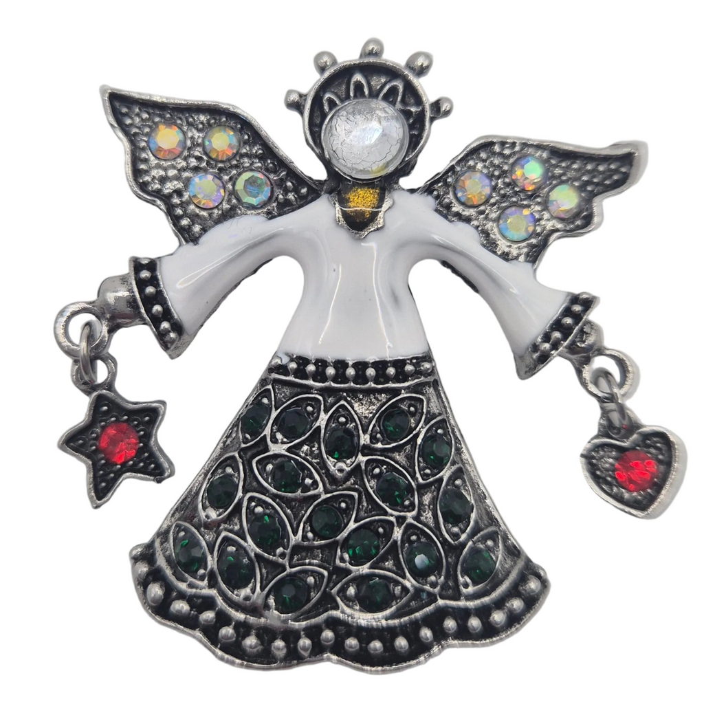 A silver-toned angel brooch featuring a white enamel body, dark green teardrop stones on the skirt, iridescent stones on the wings, and red heart and star accents hanging from the hands, shown on a plain white background.