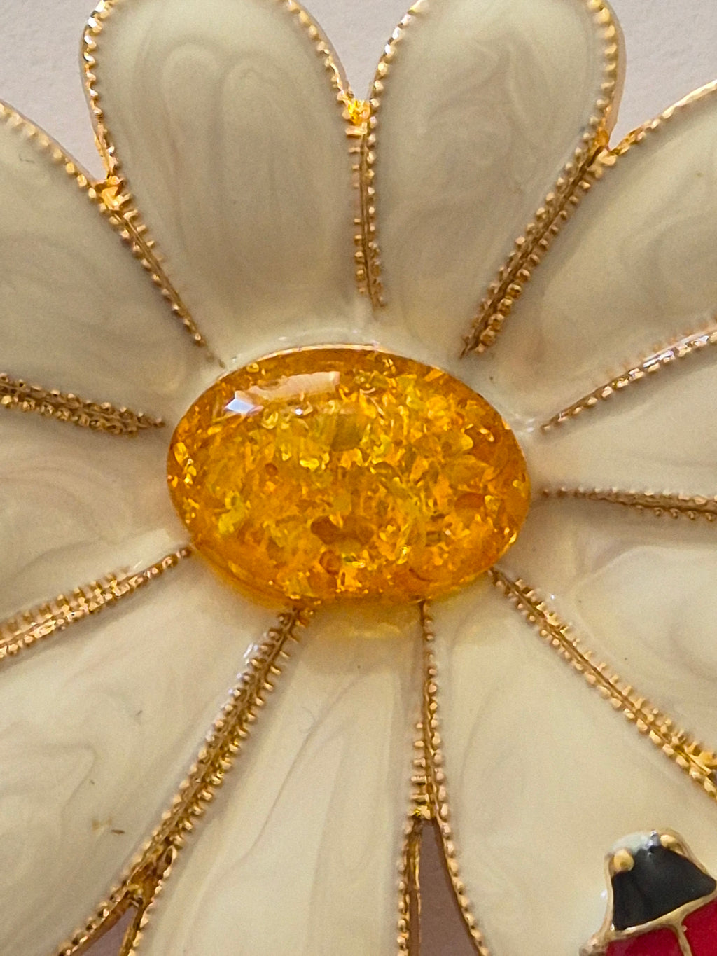 daisy flower decorative brooch with a yellow center and gold accents.