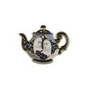 A Halloween-themed enamel pin shaped like a teapot, featuring two white ghosts with black outlines and gold trim against a black and silver patterned background.