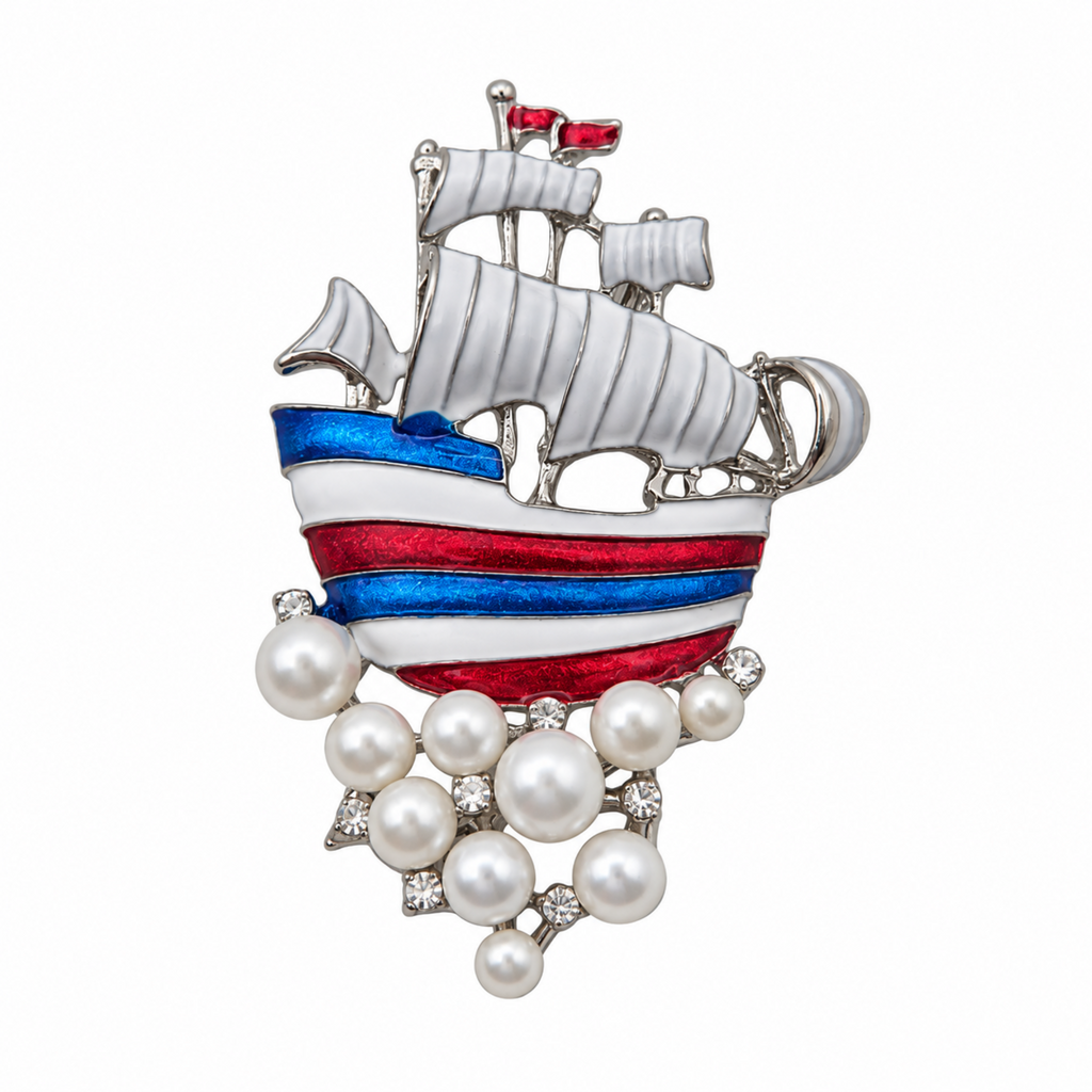 A silver-toned ship brooch featuring white sails, red and blue striped hull details, and a cluster of white pearls at the bottom, shown on a plain white background.