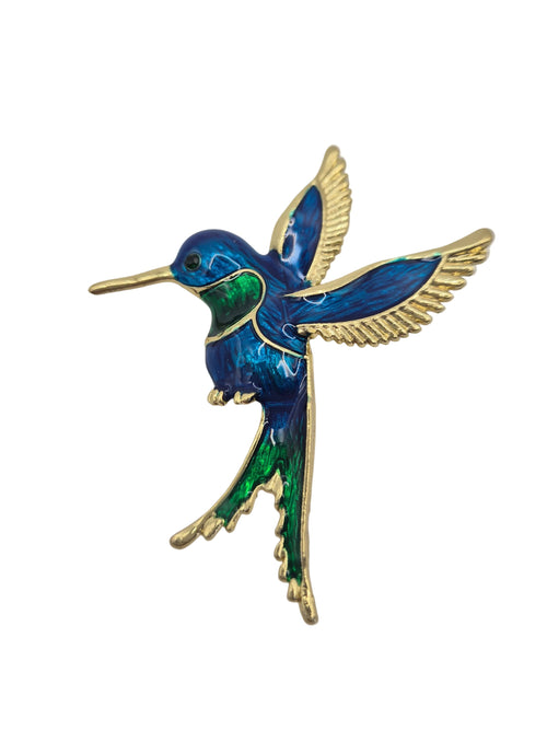 A hummingbird brooch featuring vibrant blue and green enamel with gold-tone metal outlines and wings, set against a plain white background.