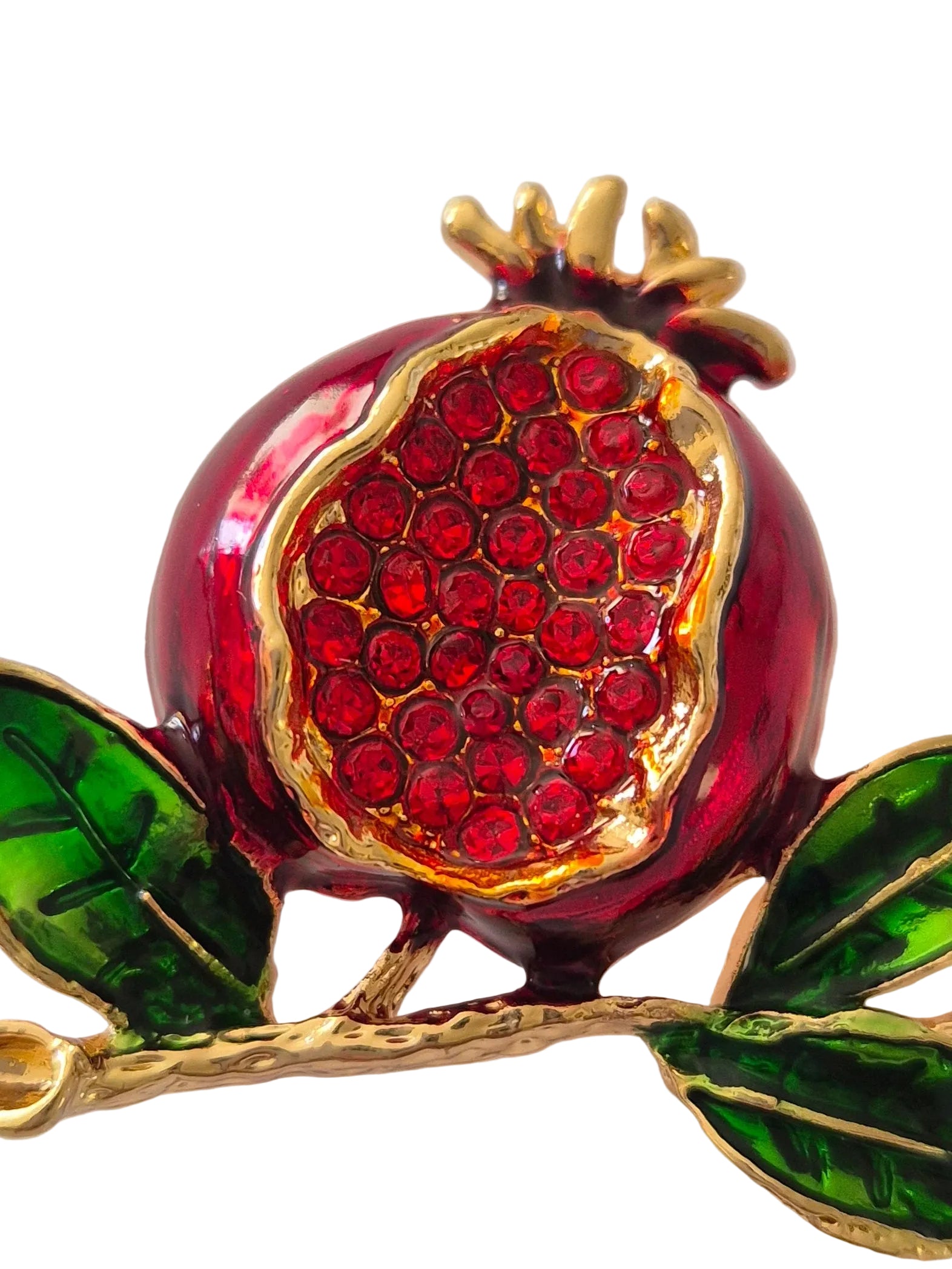 Pomegranate brooch with red gemstones and green leaves on a white background