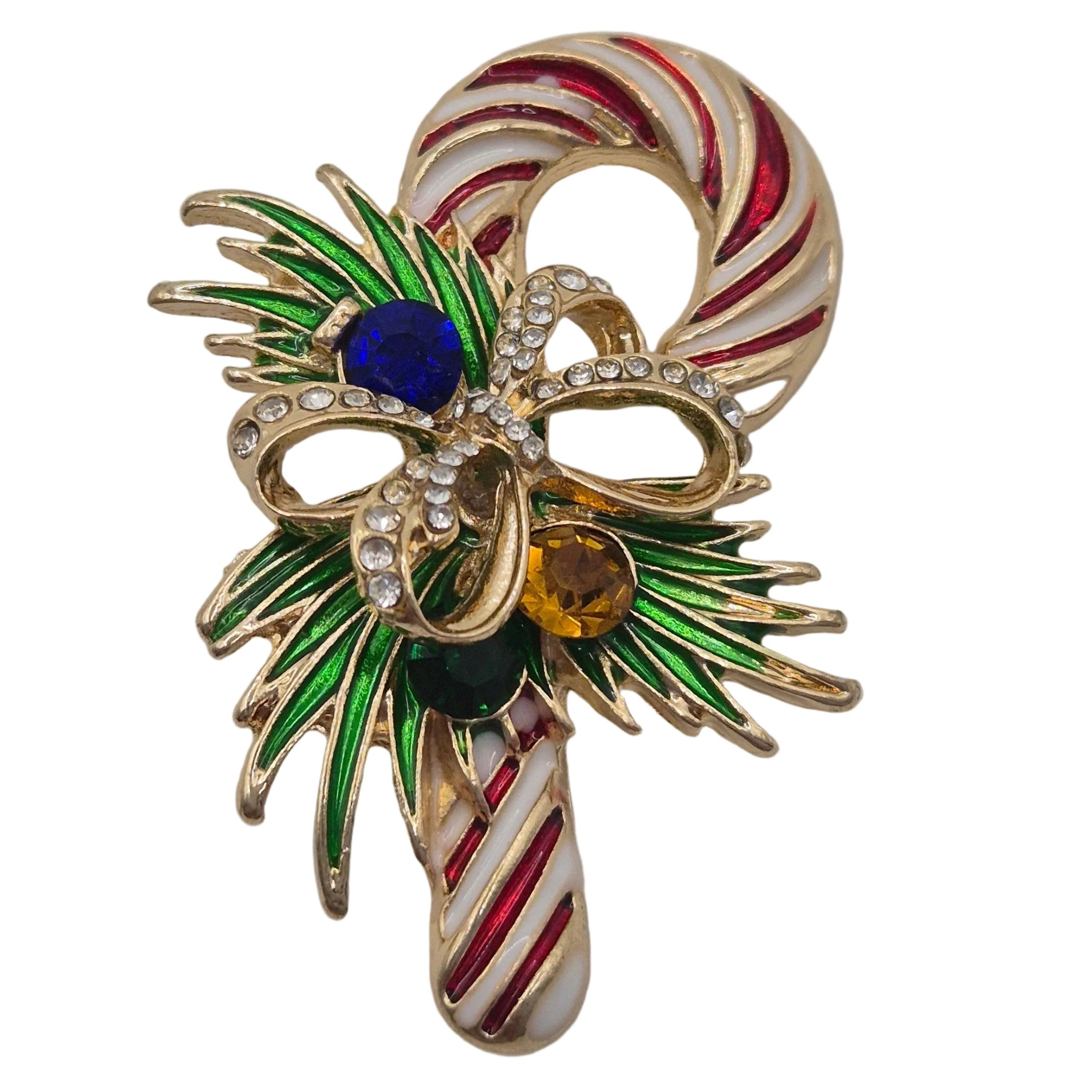 A festive Christmas candy cane brooch featuring gold-tone metal, red and white enamel stripes, green leaf accents, and three colorful rhinestone-encrusted gems in blue, amber, and dark green, set against a plain white background.