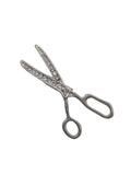 Silver scissors brooch with gemstone accents on a white background