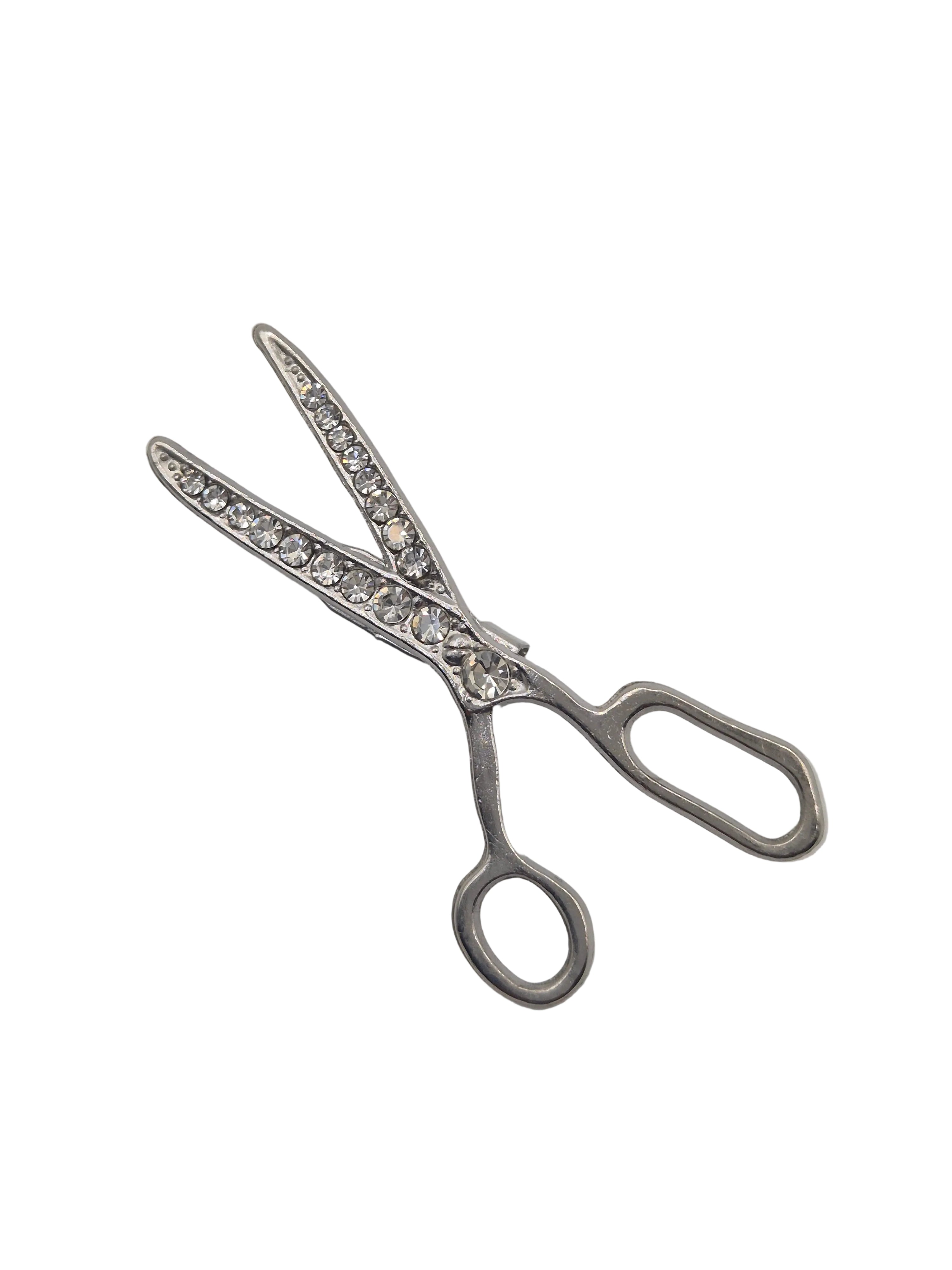 Silver scissors brooch with gemstone accents on a white background