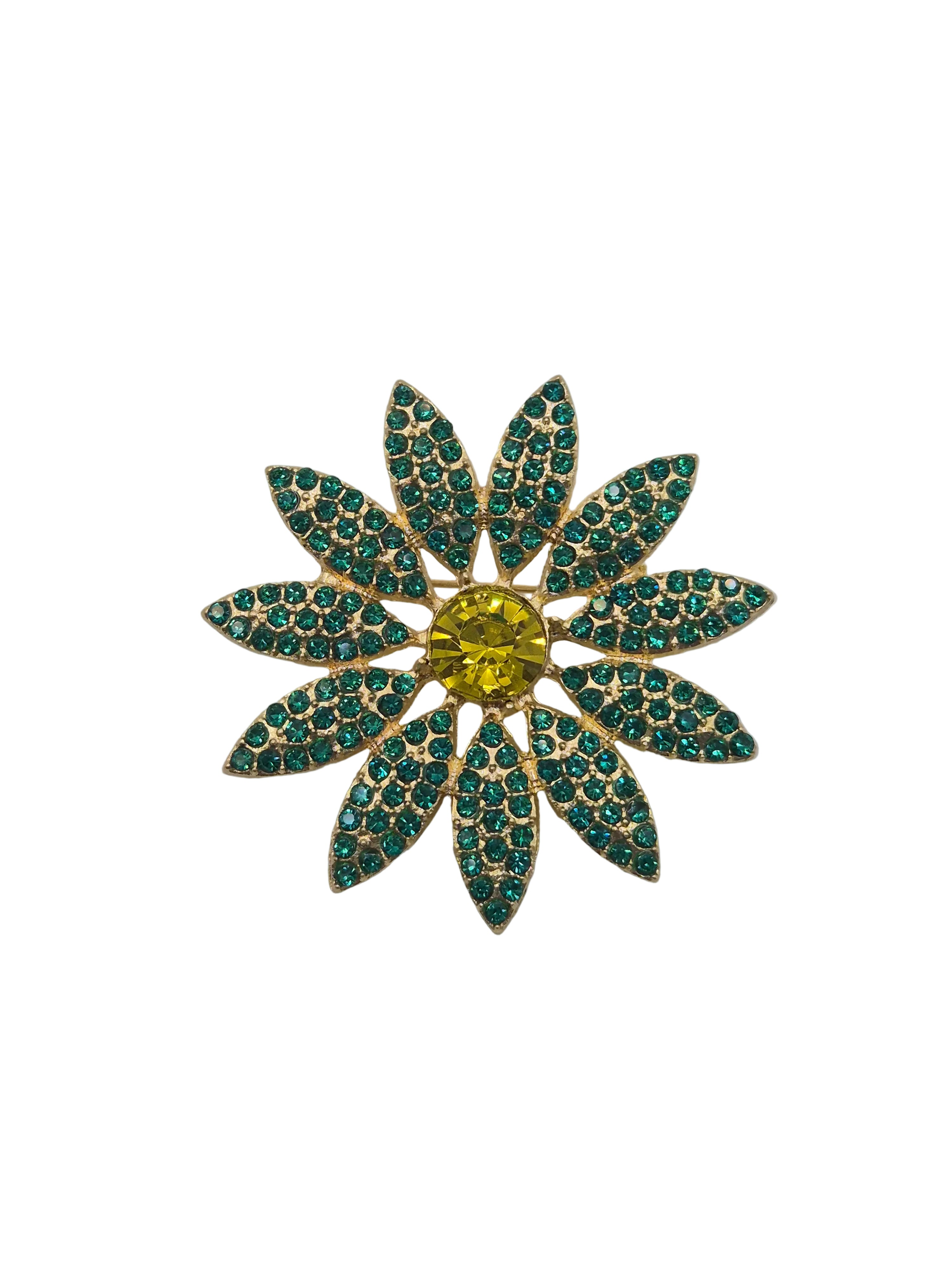 A gold-tone flower-shaped brooch with green rhinestone-encrusted petals and a yellow center stone, shown on a plain white background.