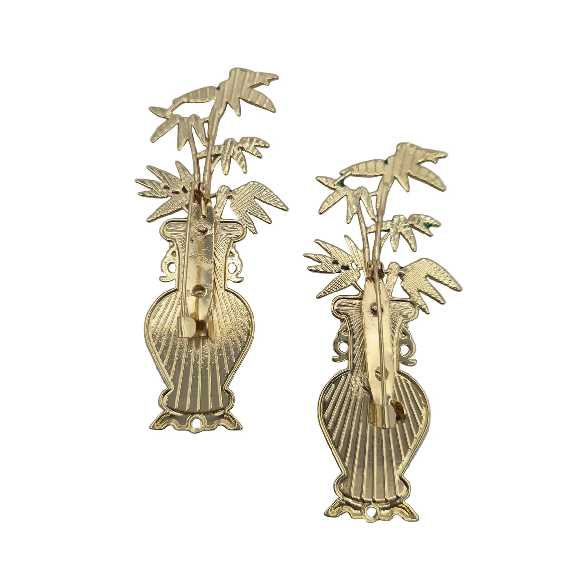 A pair of gold-tone metal brooches featuring a vase with bamboo stalks and leaves, displayed on a plain white background.