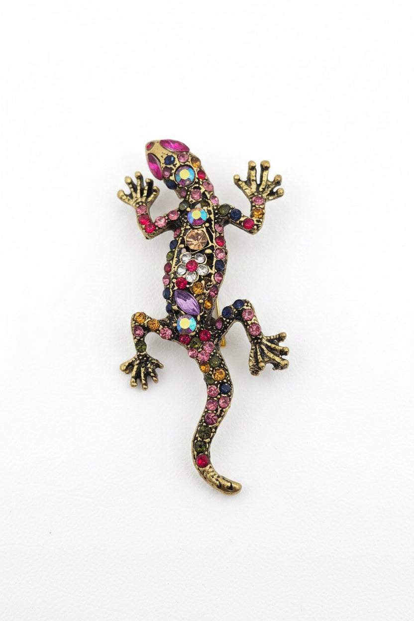 A decorative lizard or gecko-shaped brooch embellished with multicolored rhinestones and gold-tone metal, shown on a plain white background.