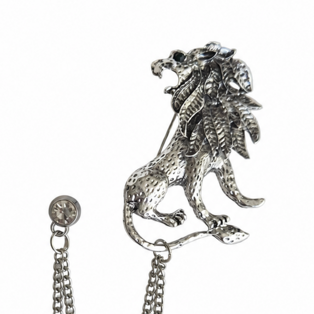 A silver-toned metal lion brooch with a textured, hammered finish, shown on a plain white background with its attached chain and button clasp visible.