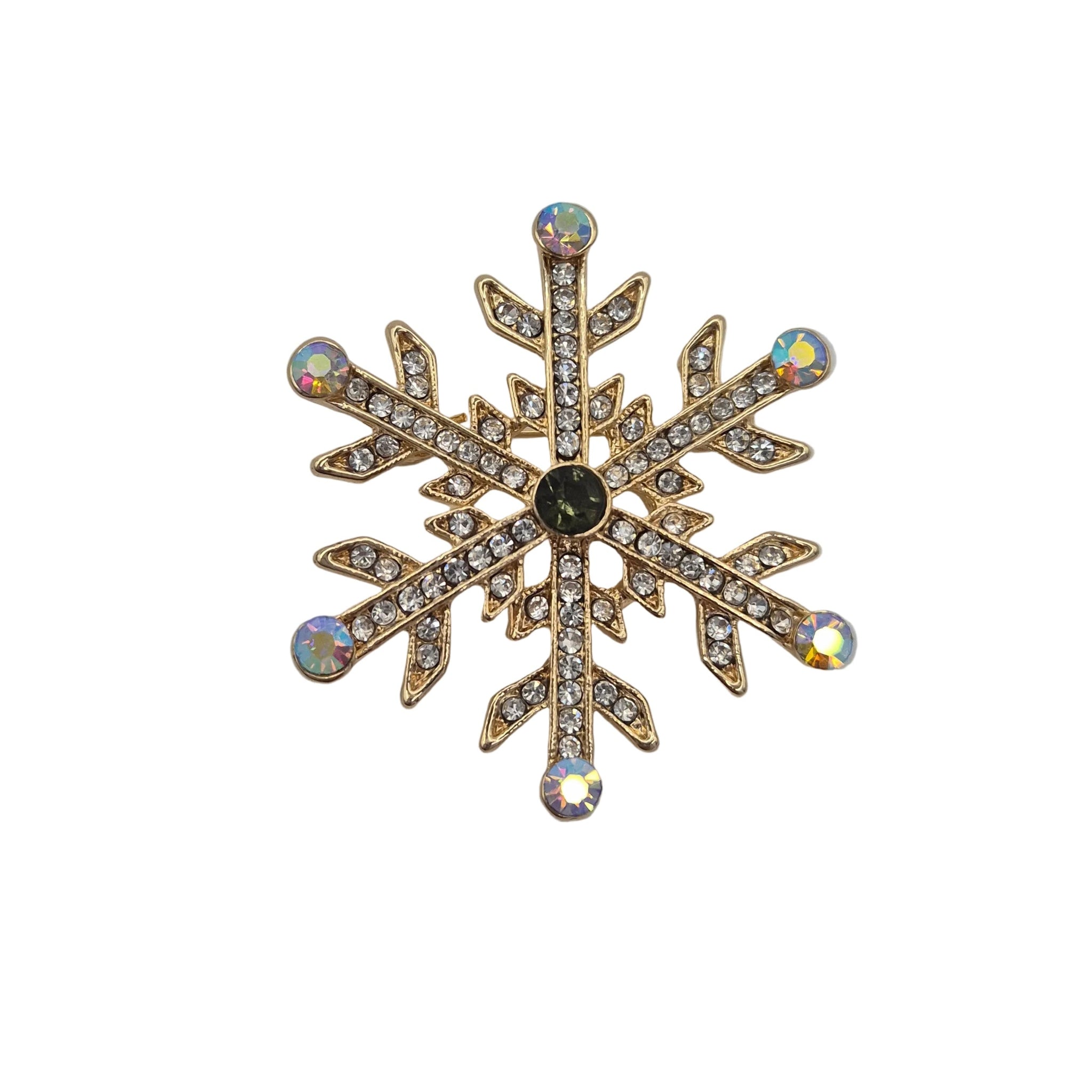 A gold snowflake-shaped brooch embellished with clear rhinestones and iridescent round crystals, featuring a dark green center stone, set against a plain white background.