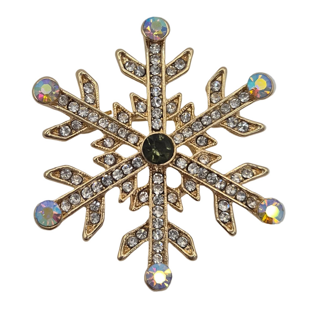 A snowflake-shaped brooch with a gold-tone metal frame, set with clear rhinestones and featuring iridescent and dark center stones, isolated on a white background.