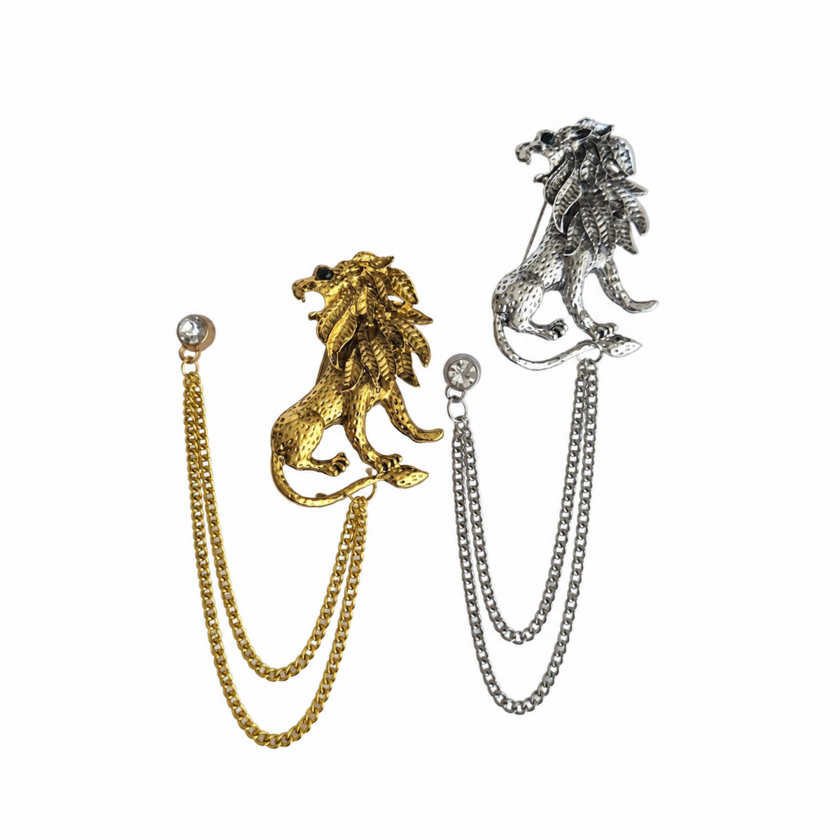 Two lion head chain brooches shown on a plain white background, one in gold-tone metal and one in silver-tone metal, each with a double-strand chain hanging from the lion head.