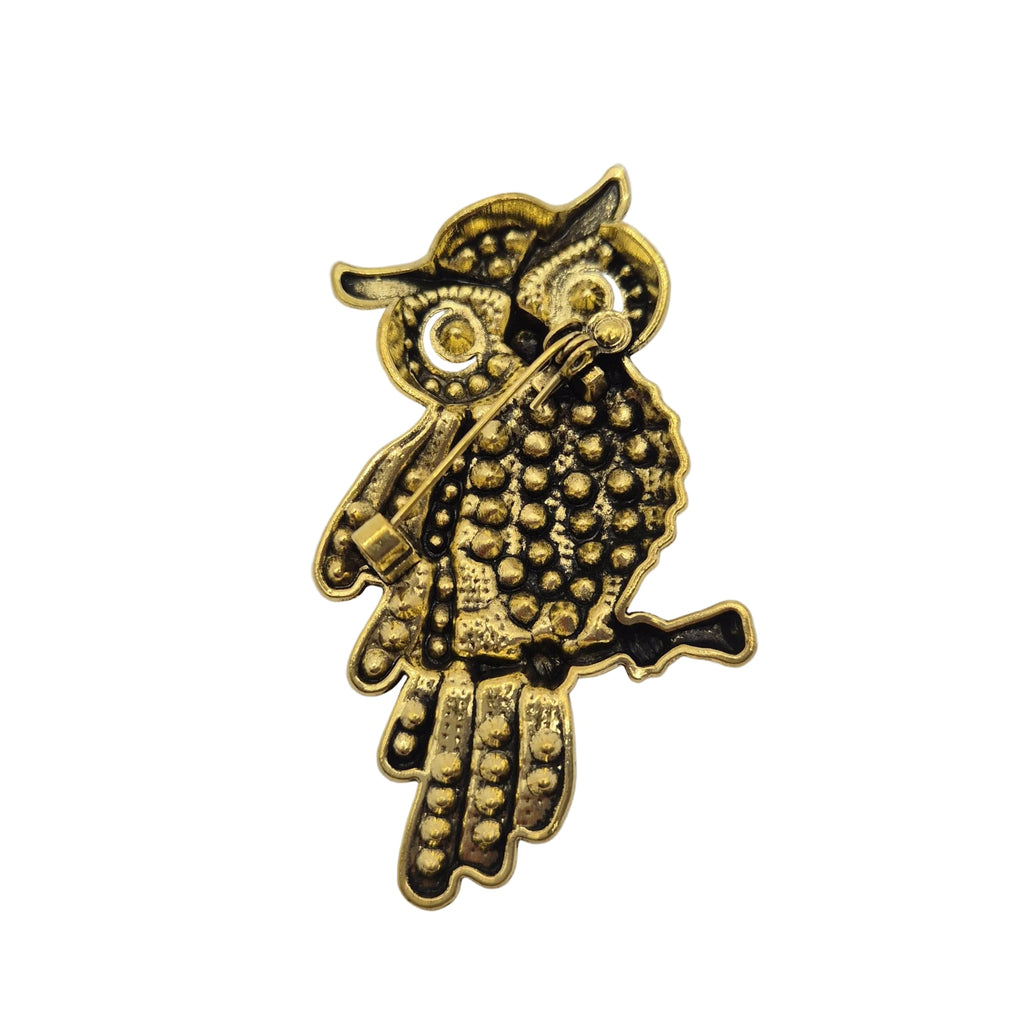 A small gold-toned bird-shaped accessory with textured dot detailing and dark recessed accents, photographed on a plain white background.