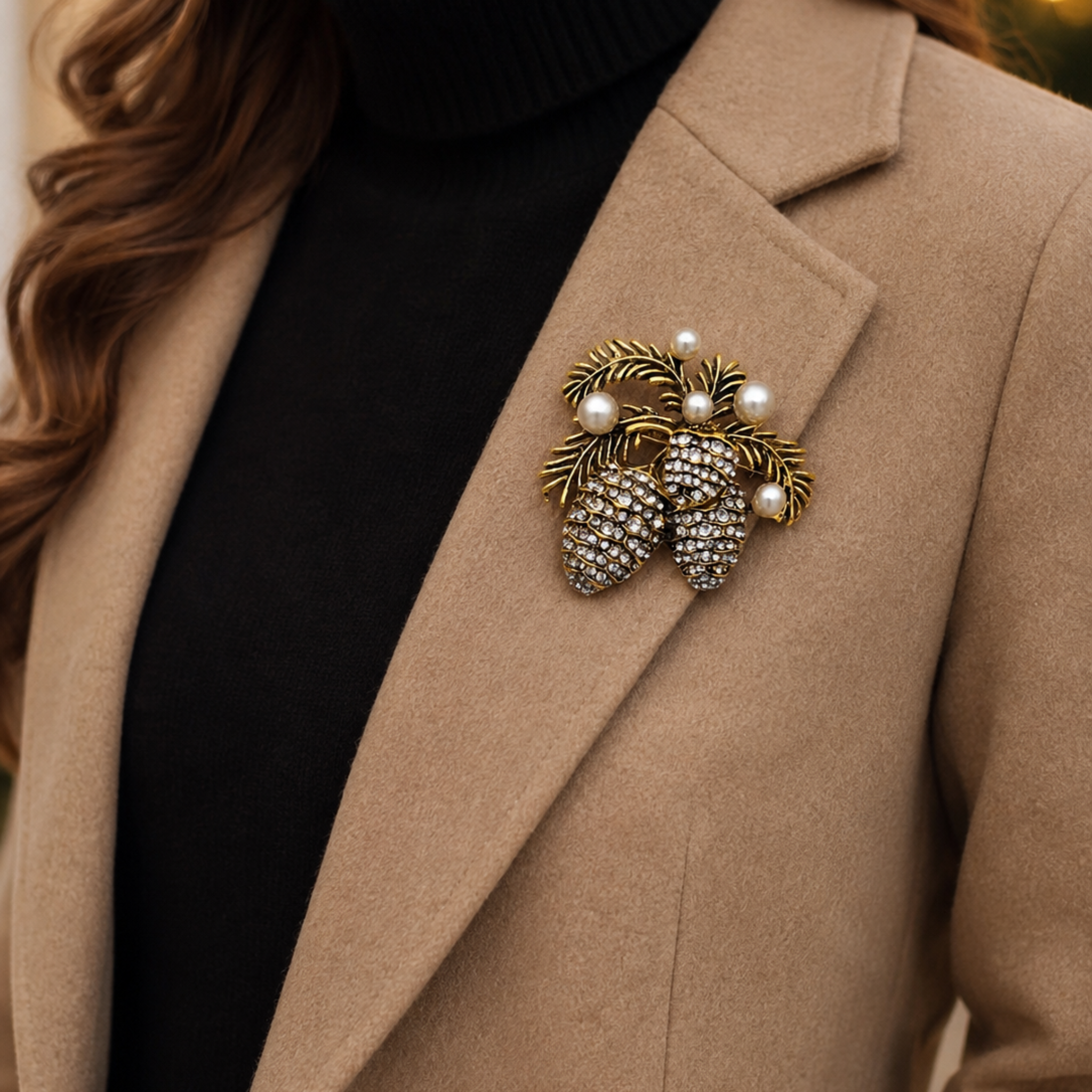 A close-up of a woman wearing a beige coat over a black turtleneck, featuring a decorative brooch shaped like pinecones with pearl-like accents and gold-toned leaf details on the left lapel.