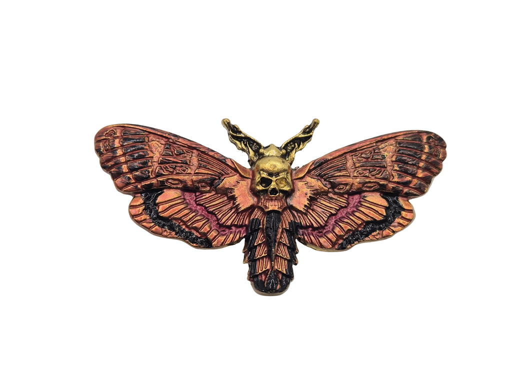 Moth-shaped brooch with skull design on a white background