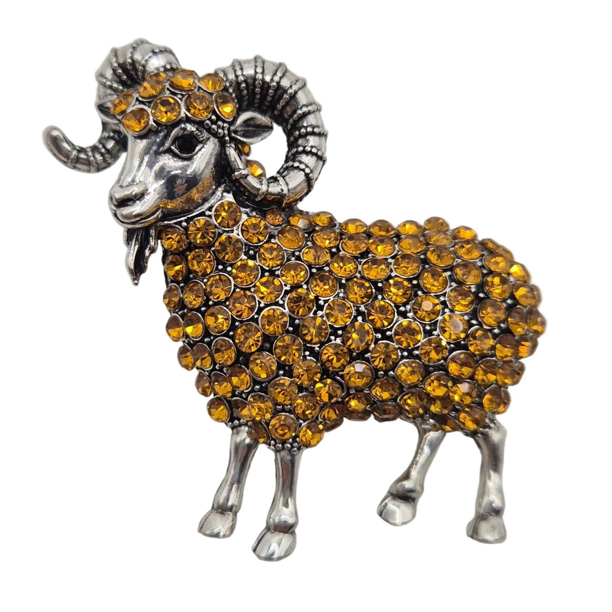 A ram-shaped brooch or pin featuring a silver-tone metal body and curled horns, covered with round amber-yellow rhinestones, shown on a plain white background.