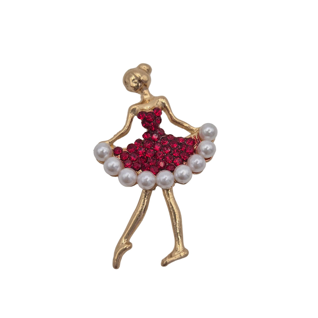 A gold-toned ballerina figurine brooch with a sparkling red crystal skirt and white faux-pearl trim, shown on a plain white background.