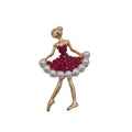 A gold-toned ballerina figurine brooch with a sparkling red crystal skirt and white faux-pearl trim, shown on a plain white background.