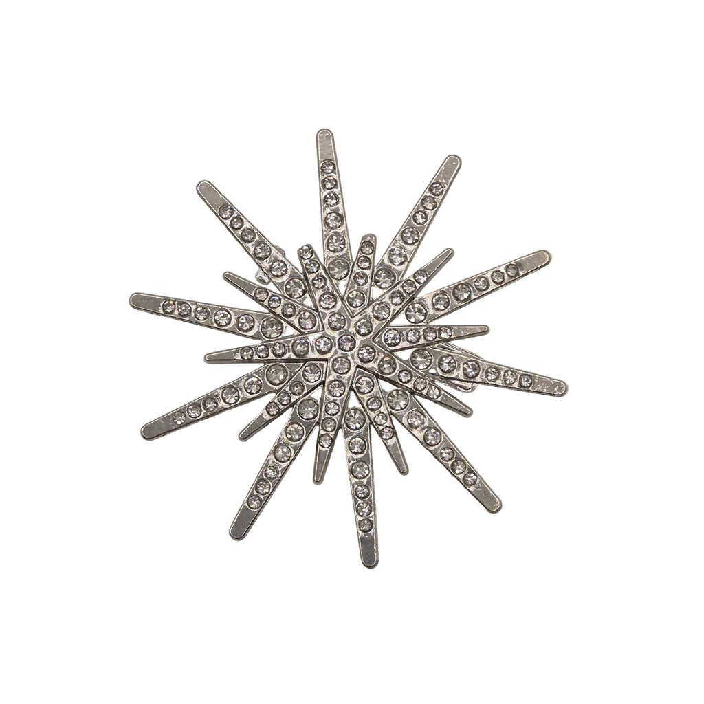 A silver-toned starburst brooch embellished with clear rhinestones, displayed on a white background.