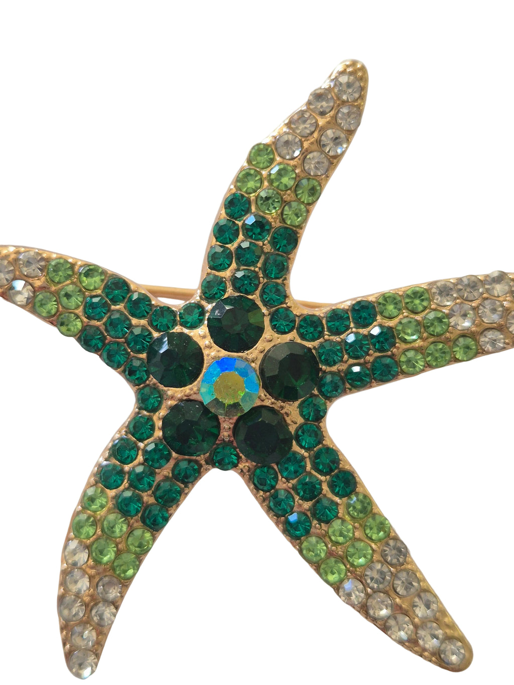 Starfish-shaped brooch with green and gold gemstones on a white background