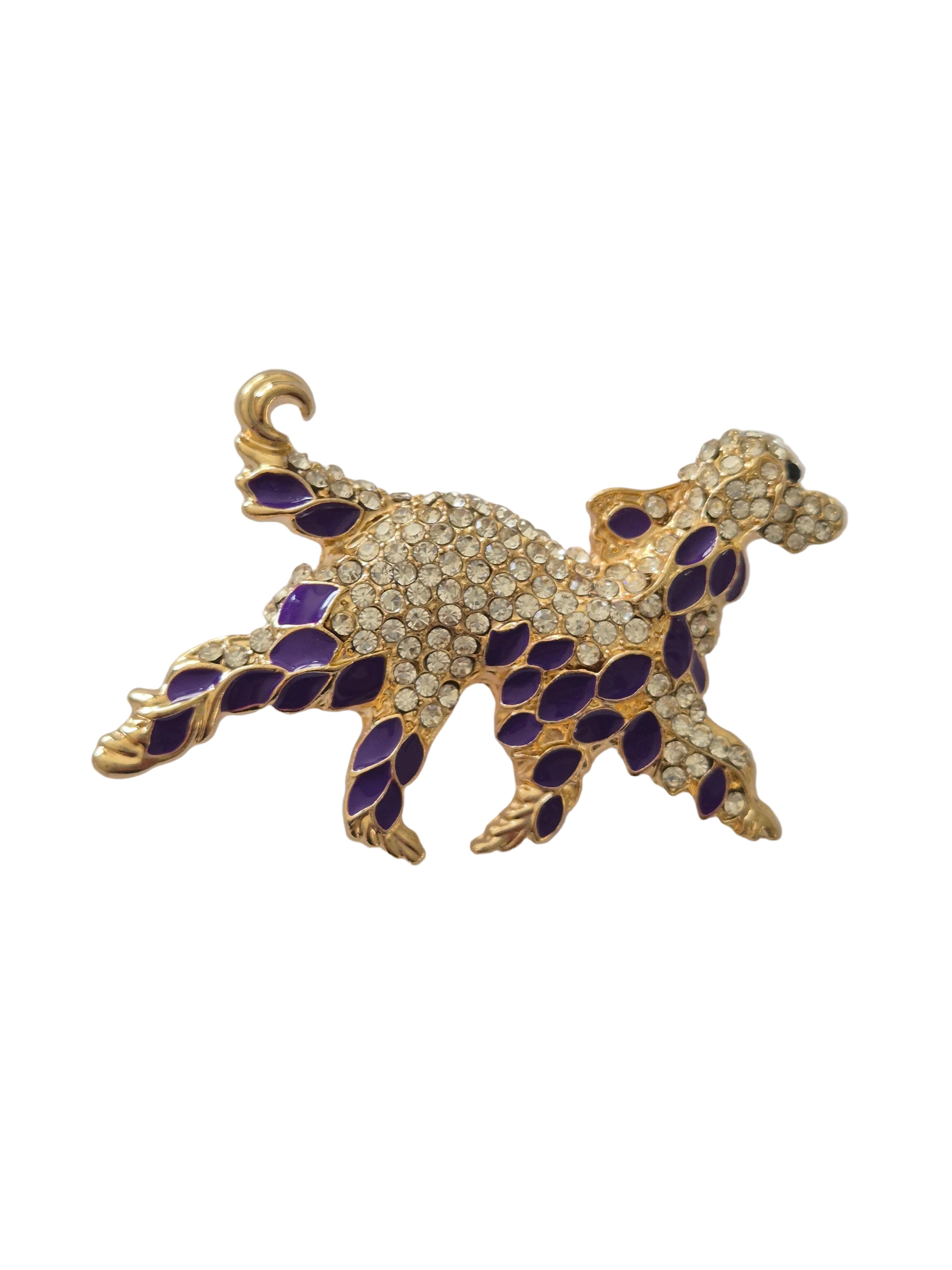 Gold and purple dog shaped brooch on a white background