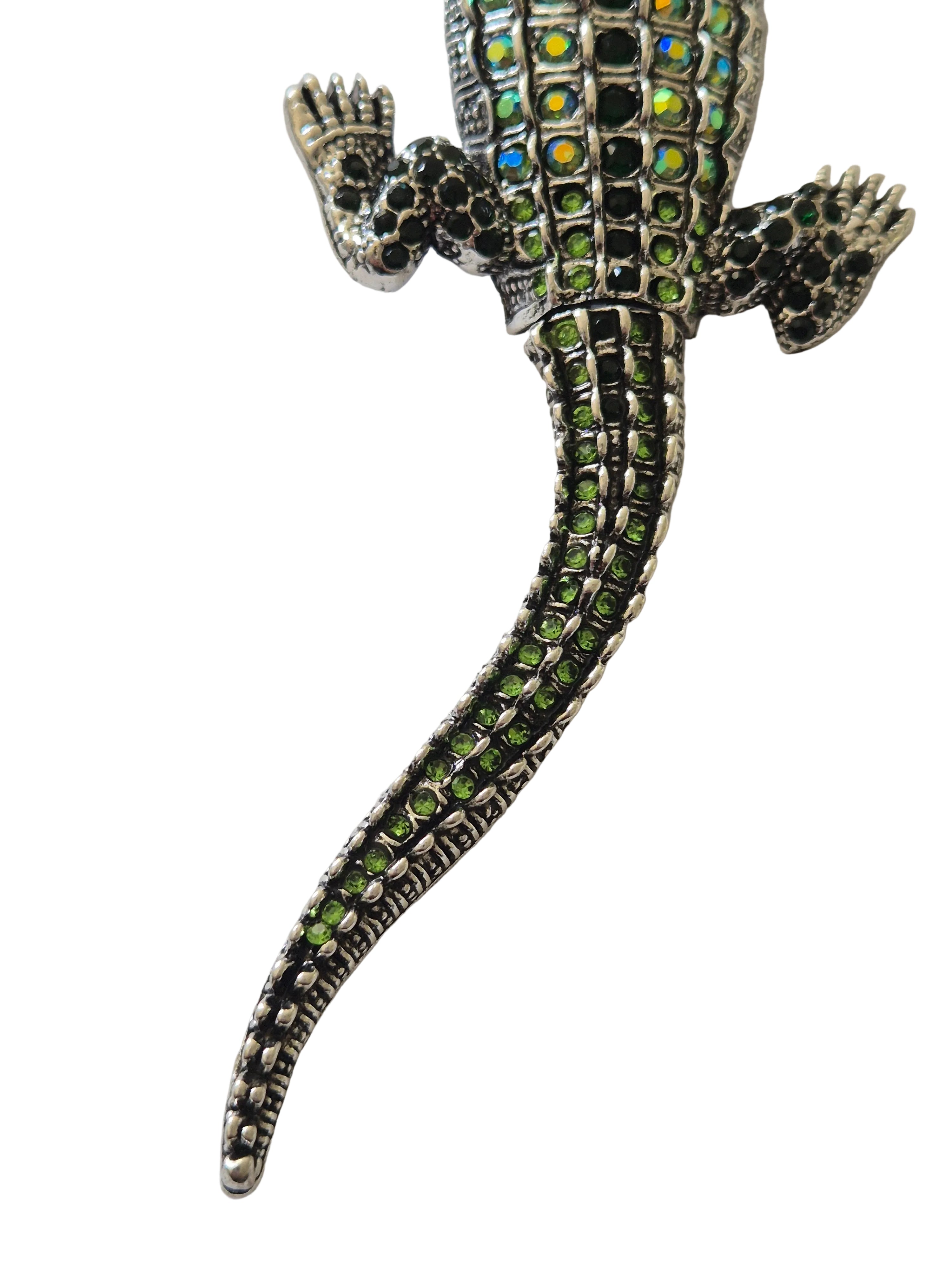 Decorative crocodile brooch with green and black details on a white background