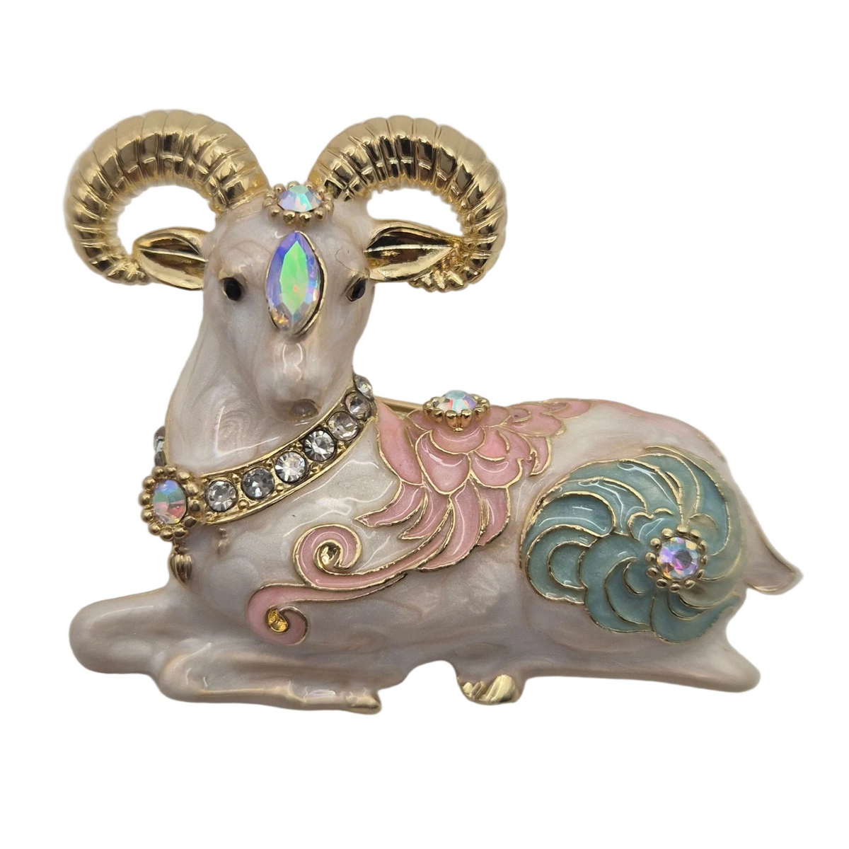 A decorative ram brooch with gold-toned horns and trim, a cream body, pink and teal enamel patterns, and iridescent rhinestone accents, shown on a plain white background.