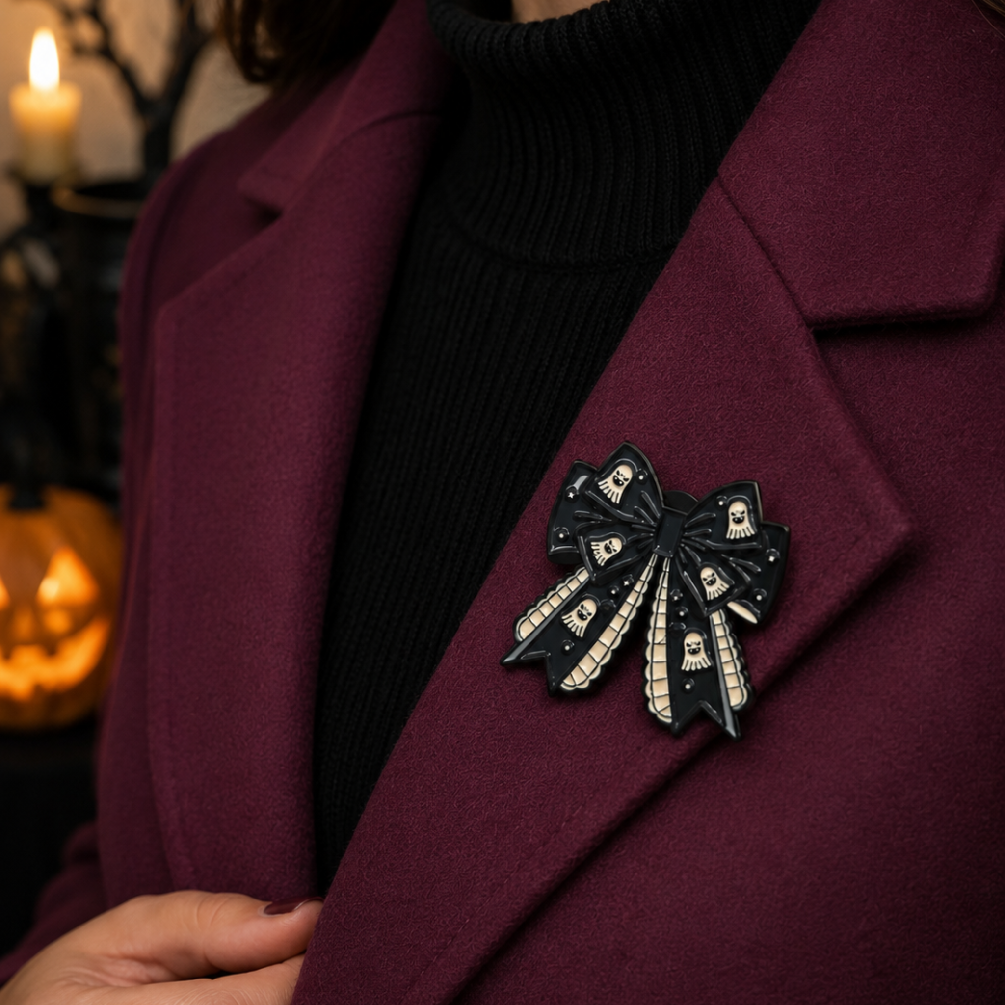 A close-up of a person wearing a burgundy coat over a black turtleneck, featuring a black bow-shaped brooch embellished with white skull and crossbones on the lapel.